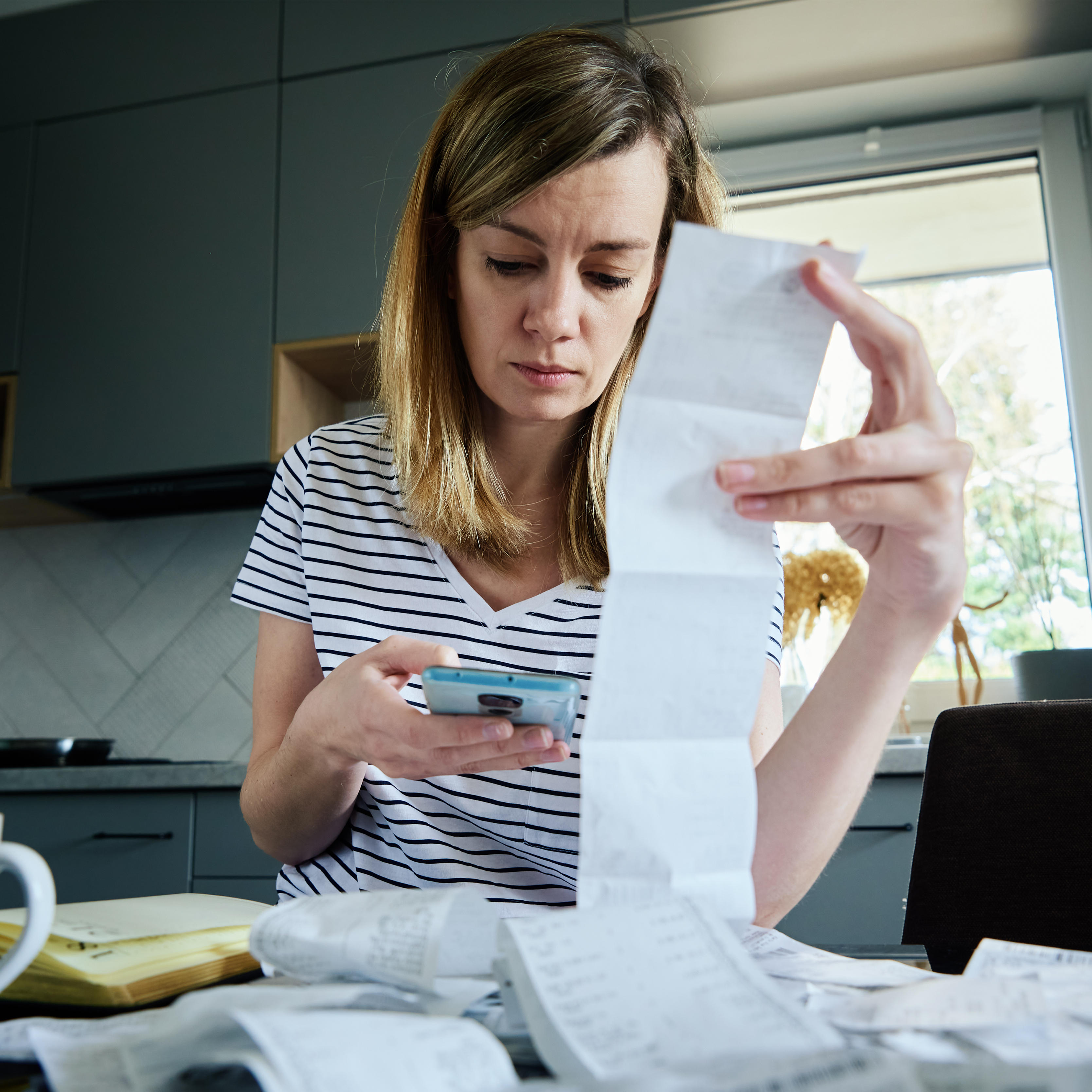 Young woman stressing out looking at her bills and phone.
