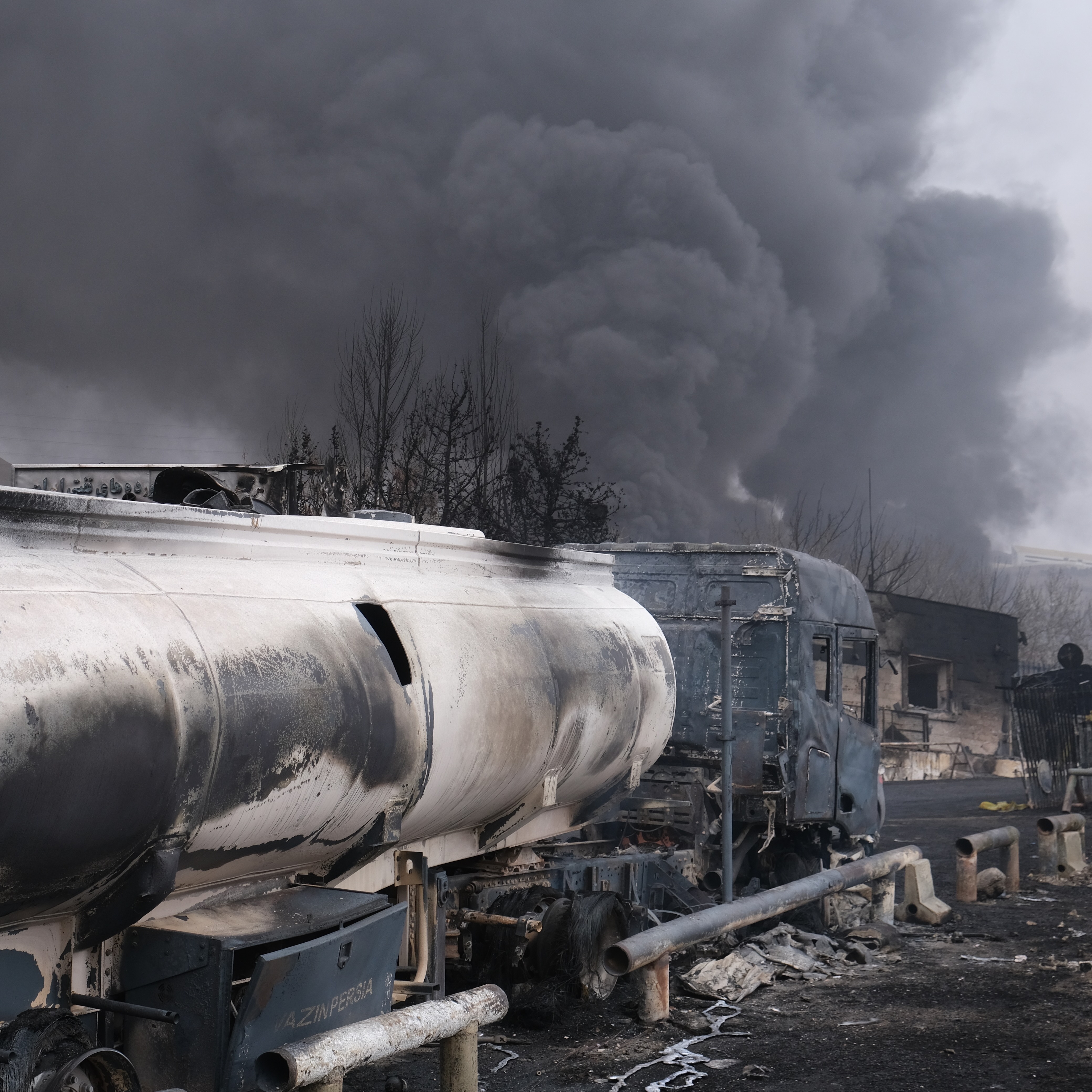 Plumes of smoke rise over the oil depot tanks hit by joint Israel-U.S. strikes.