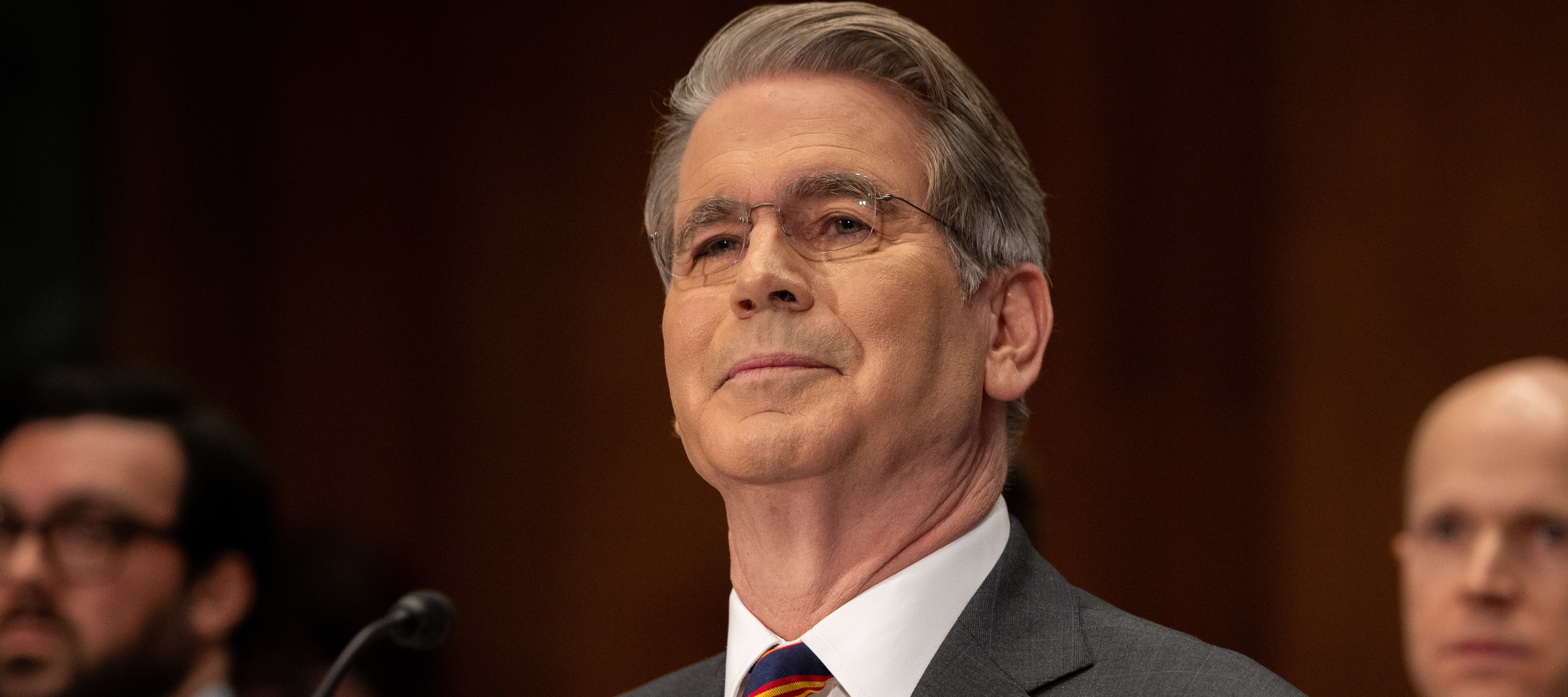 Scott Bessent speaks at a podium, smiling slightly.