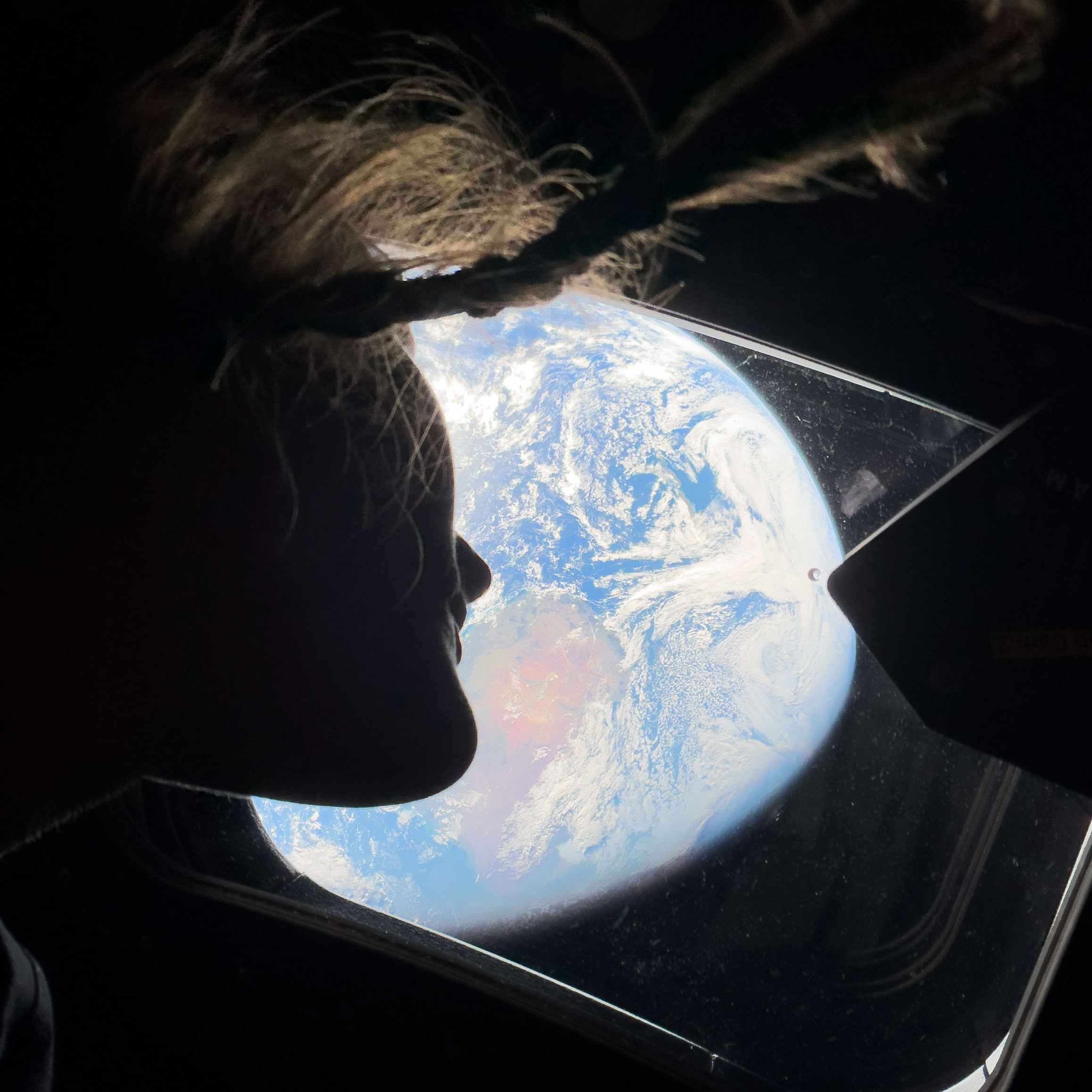 NASA astronaut and Artemis II mission specialist Christina Koch peers out of one of the Orion spacecraft's main cabin windows.