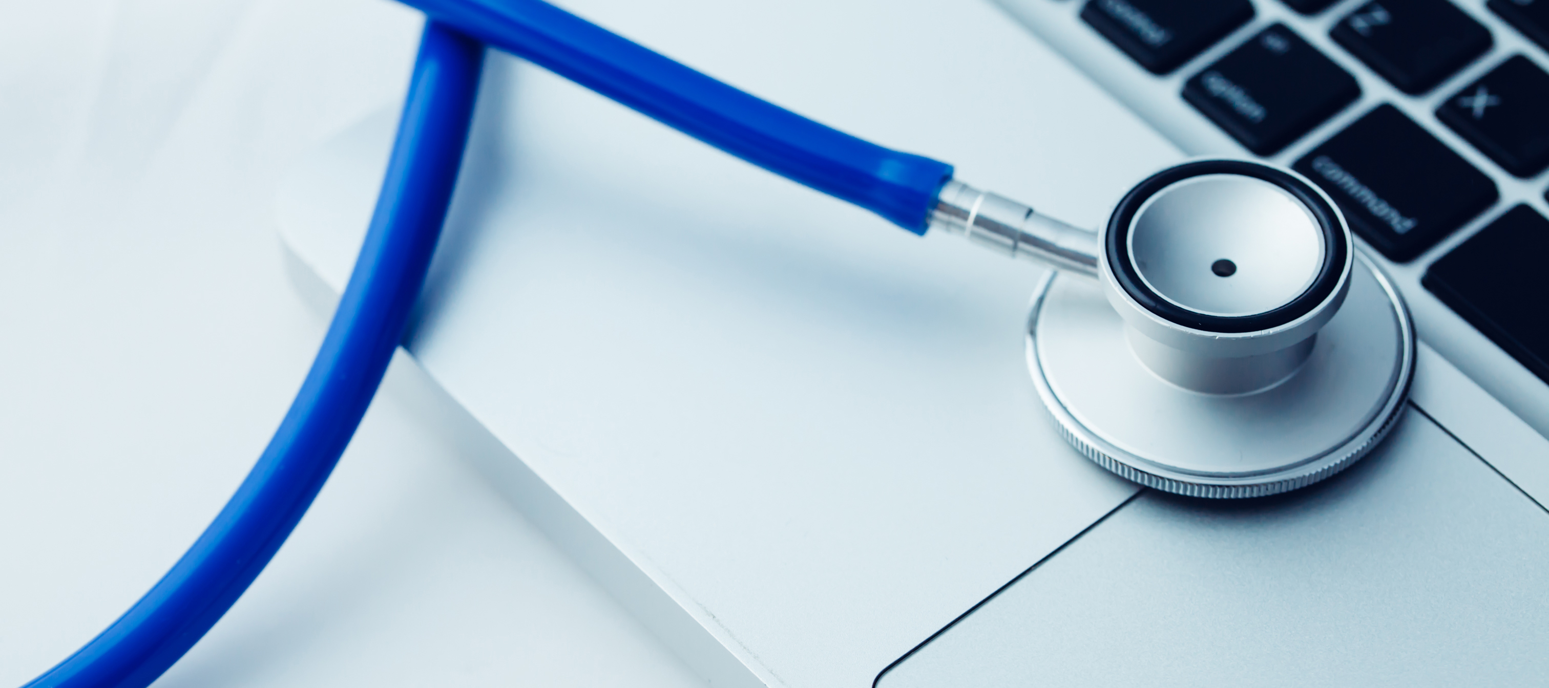 A close-up shot features a blue stethoscope placed on a silver laptop.