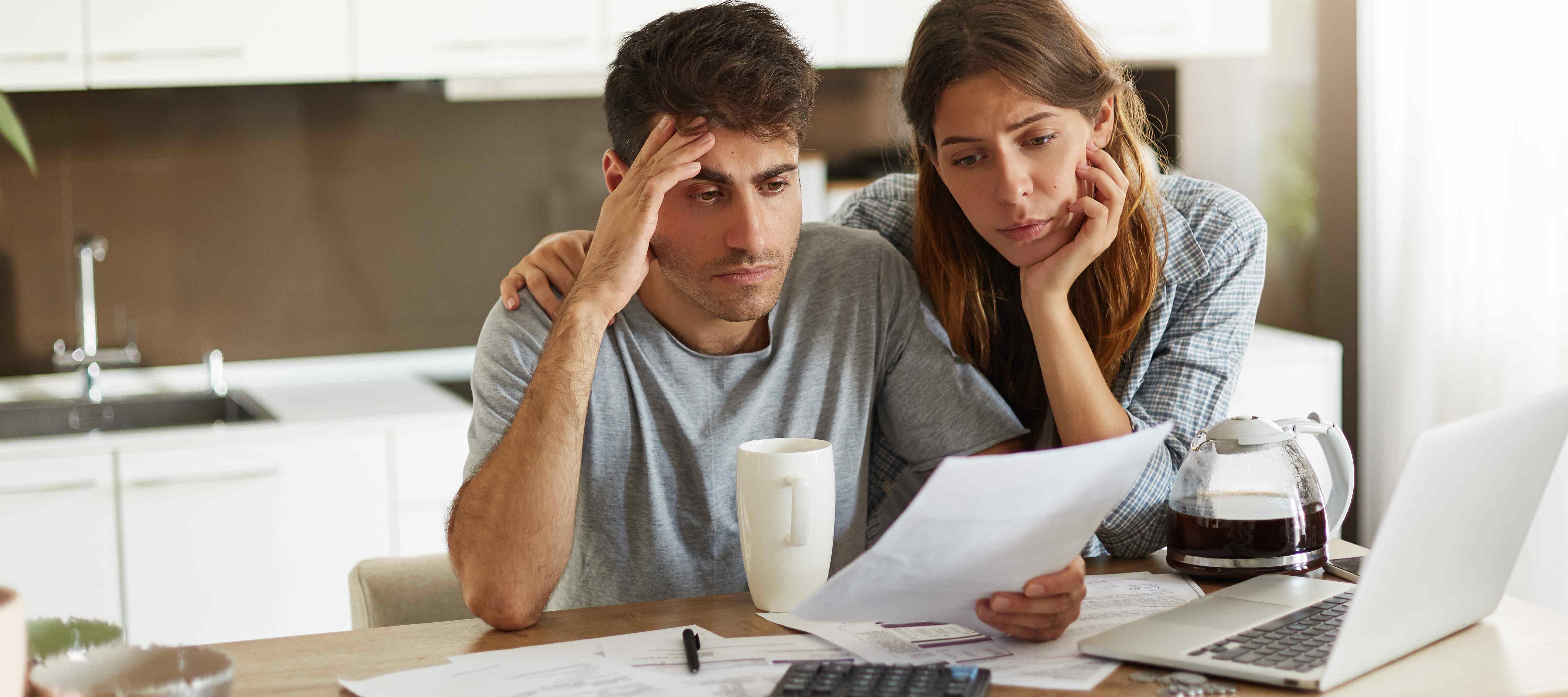 A photo of a stressed couple sitting at the kitchen counter, reviewing documents