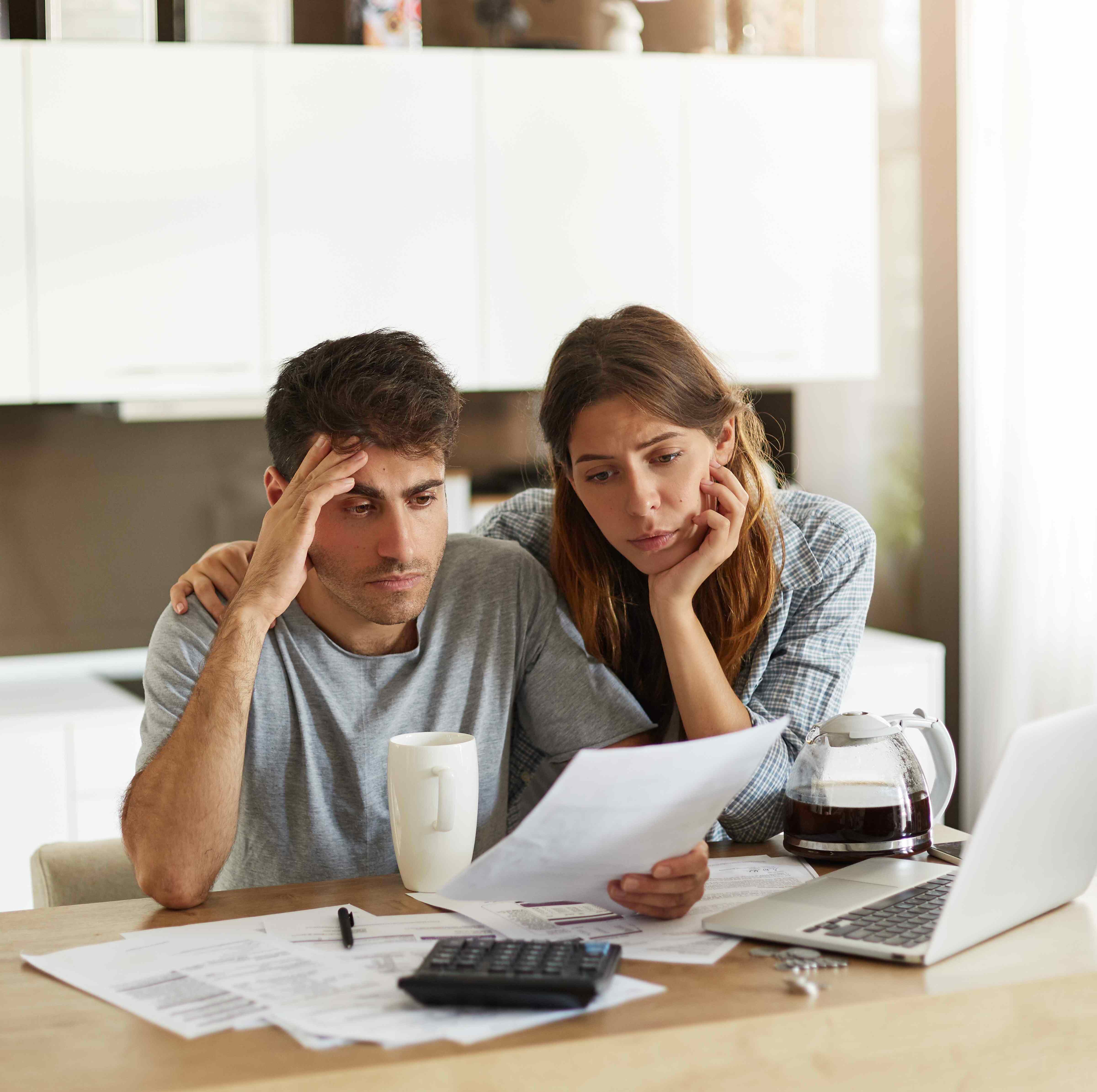 A photo of a stressed couple sitting at the kitchen counter, reviewing documents
