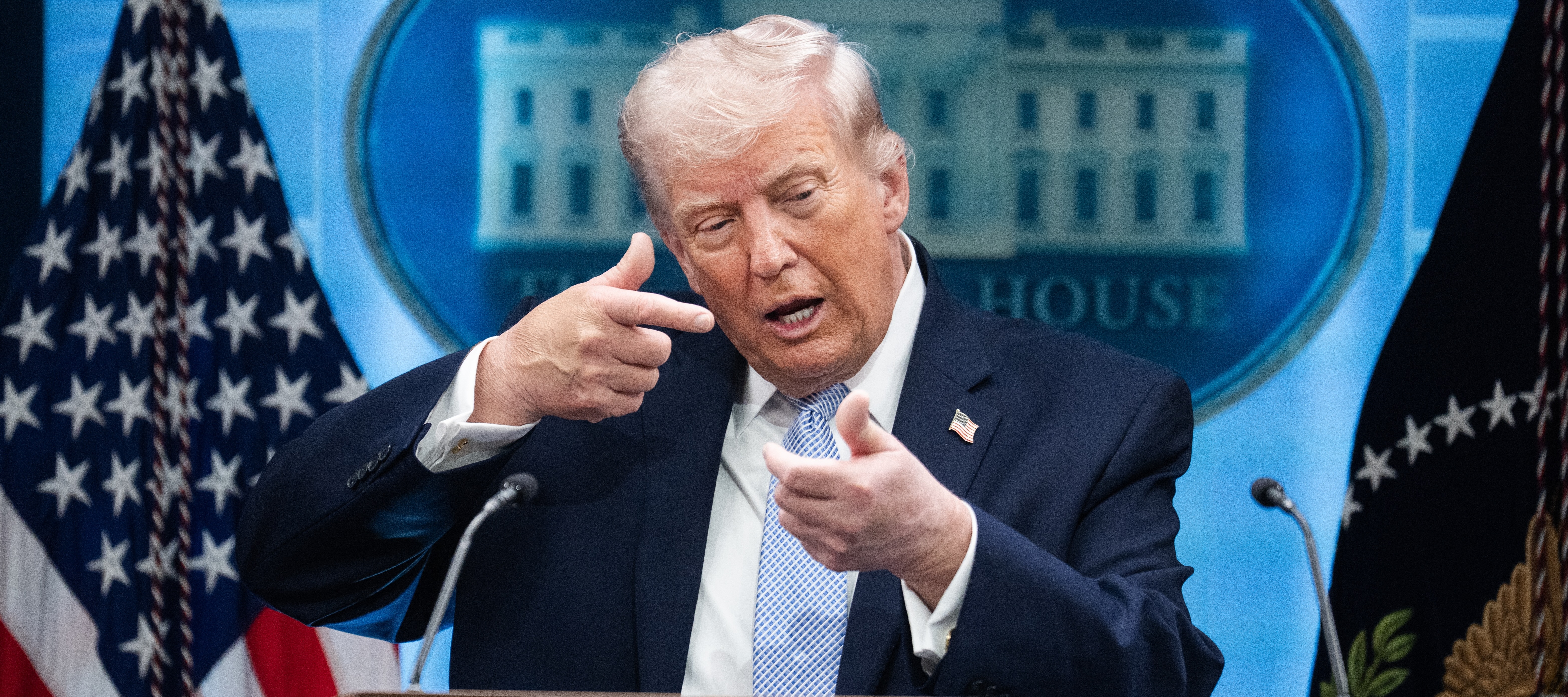 President Donald Trump mimics firing a gun during a news conference in the White House briefing room.