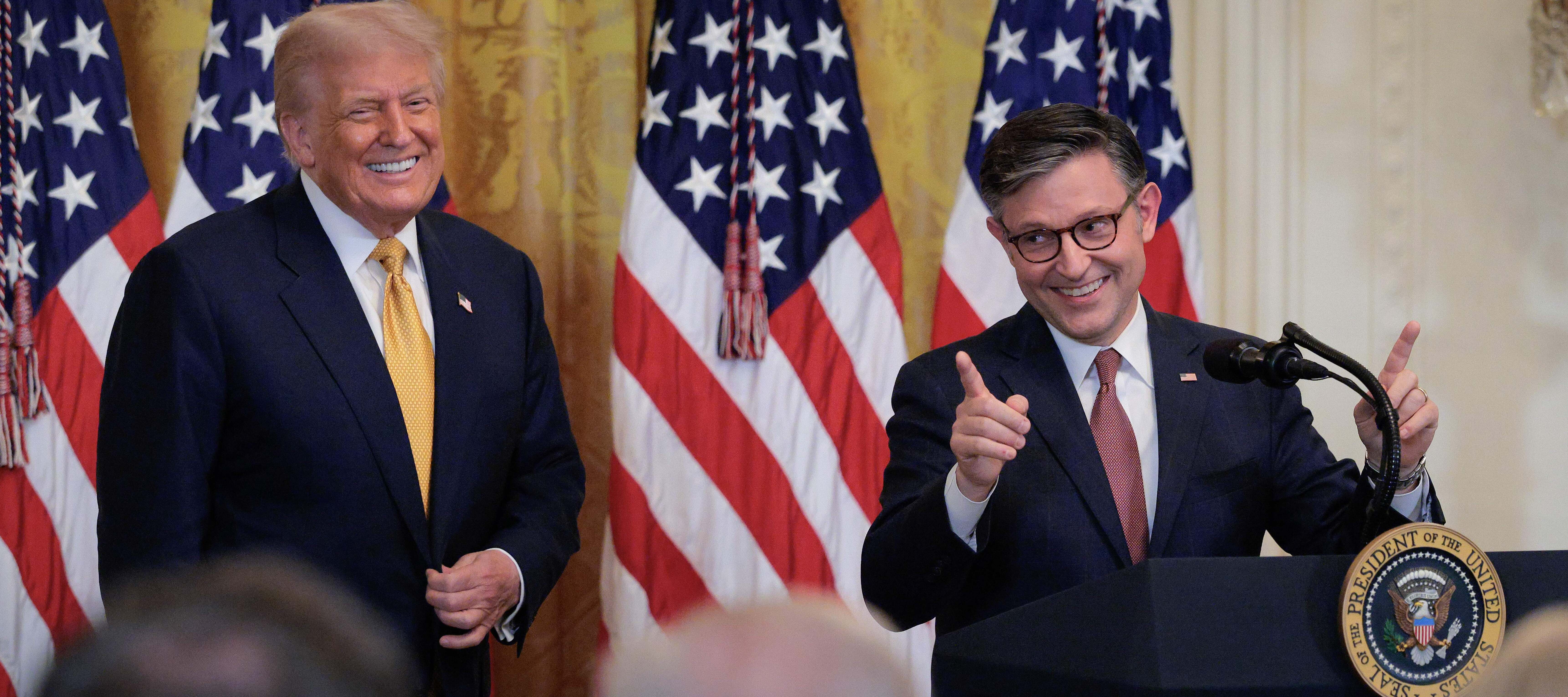 House Speaker Mike Johnson speaks as U.S. President Donald Trump looks on at a reception for Republican members of the House in the East Room of the White House on July 22, 2025