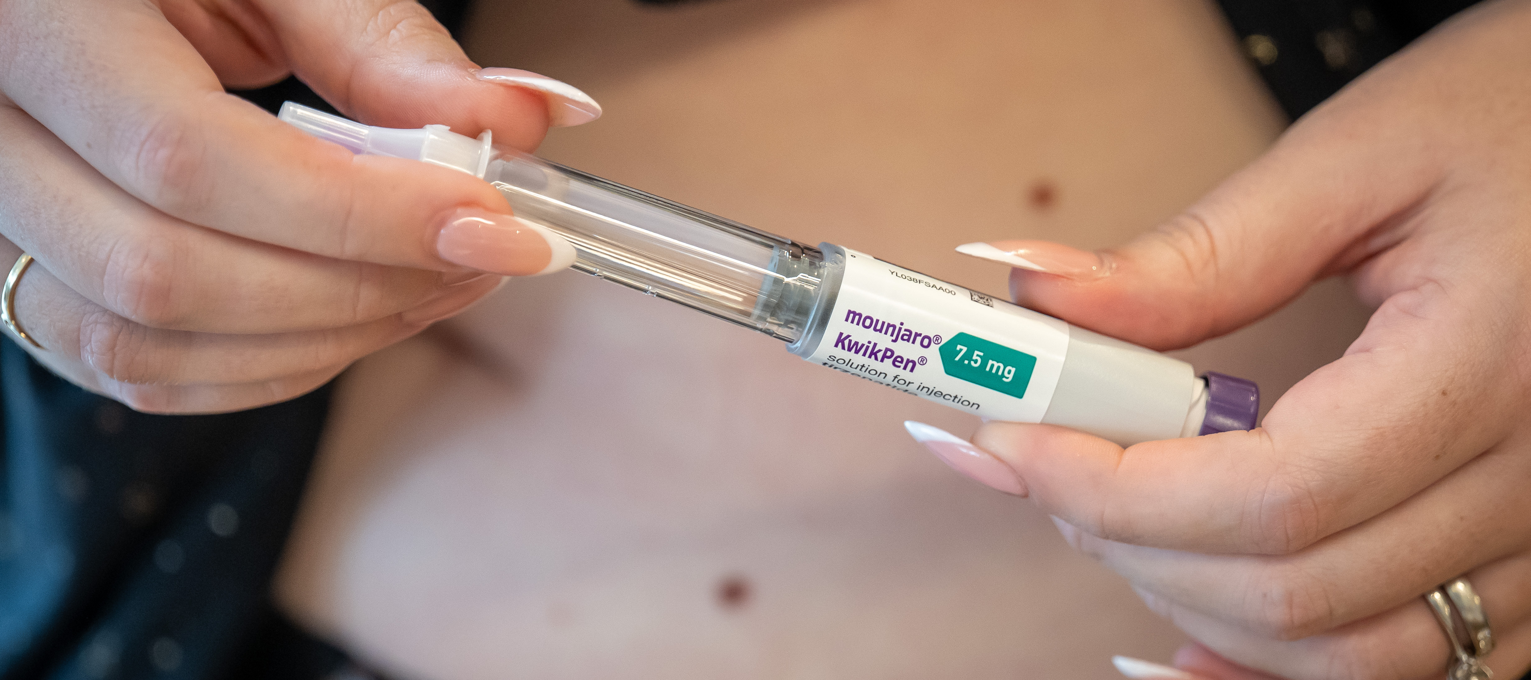 A close-up of a woman injecting a Mounjaro weight-loss jab