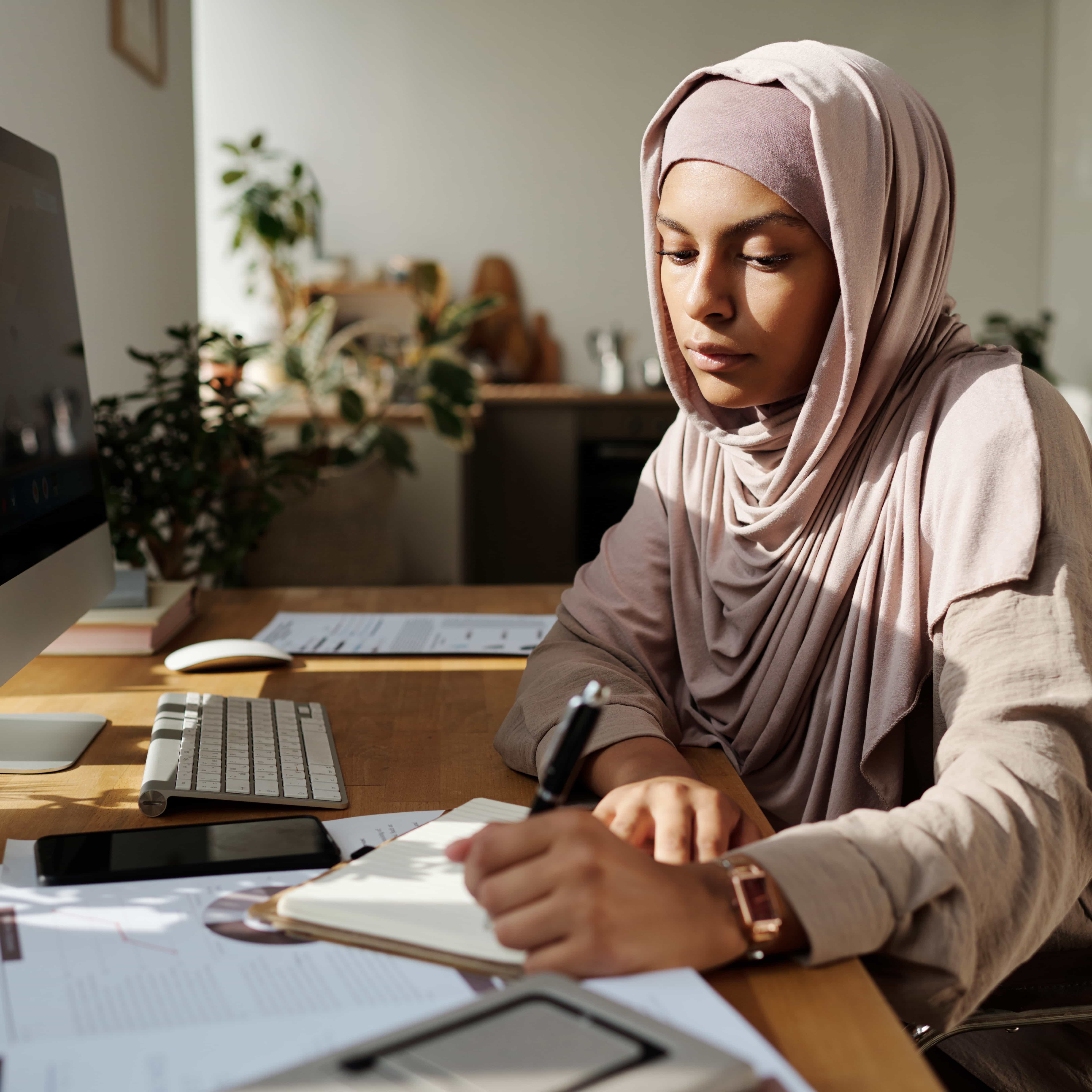 Young female employee reviewing financial documents at her computer desk