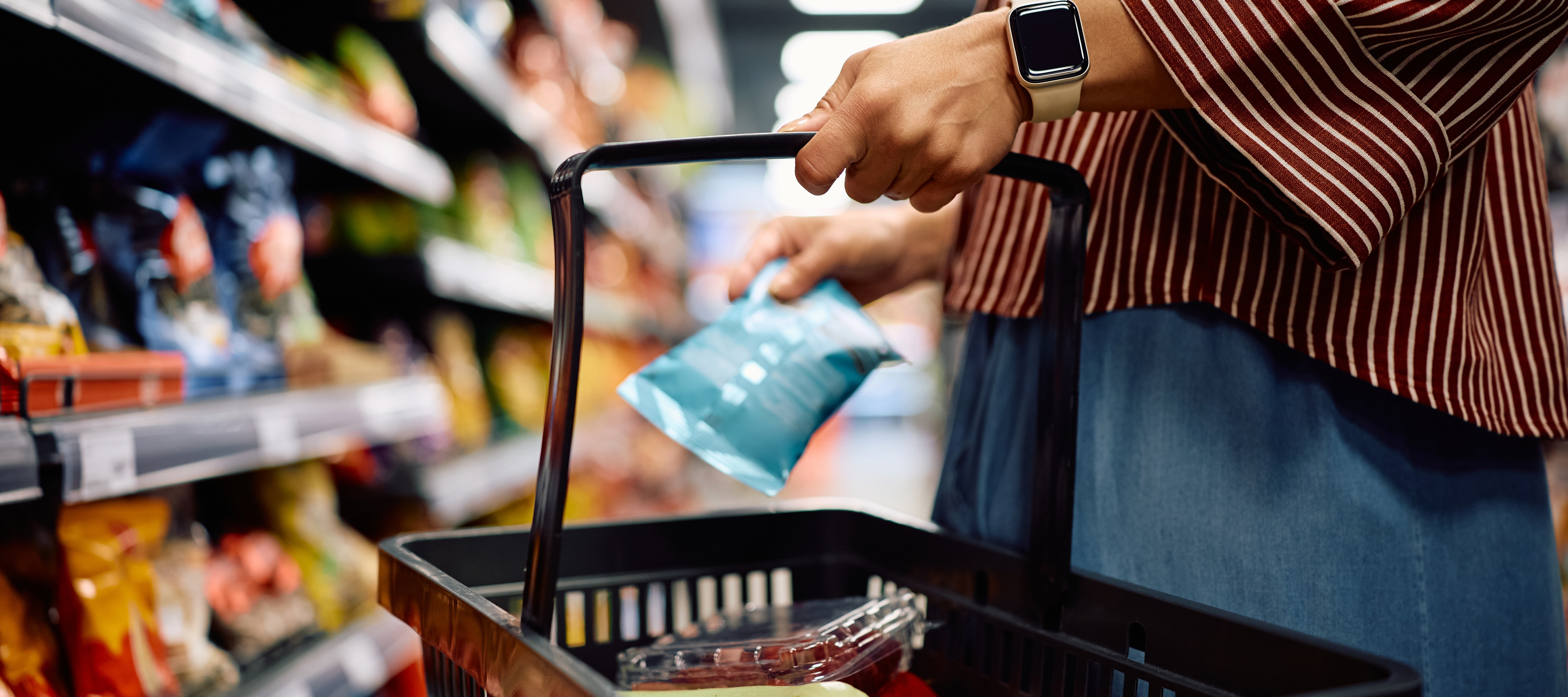 Woman adding chips to her basket at grocery store