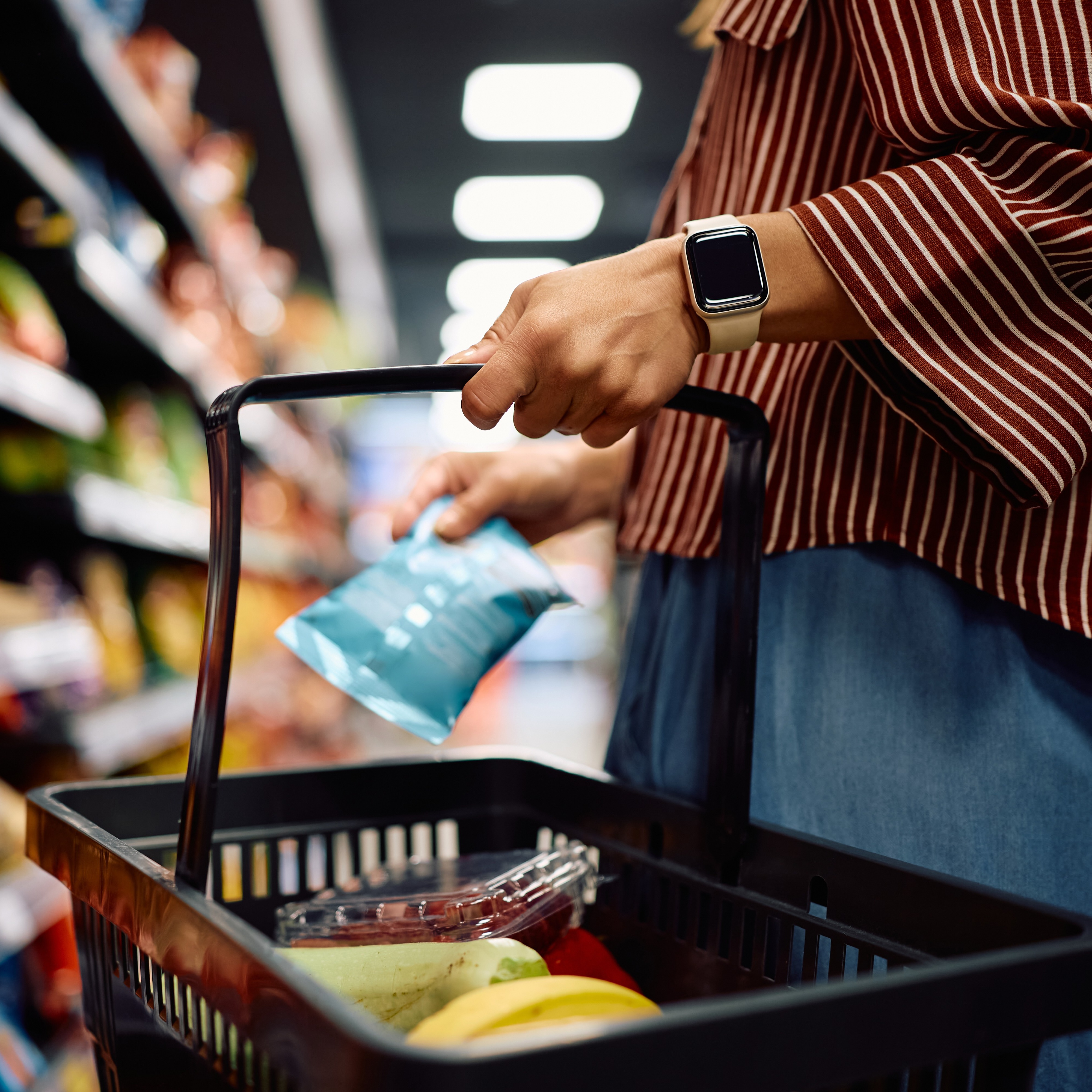 Woman adding chips to her basket at grocery store
