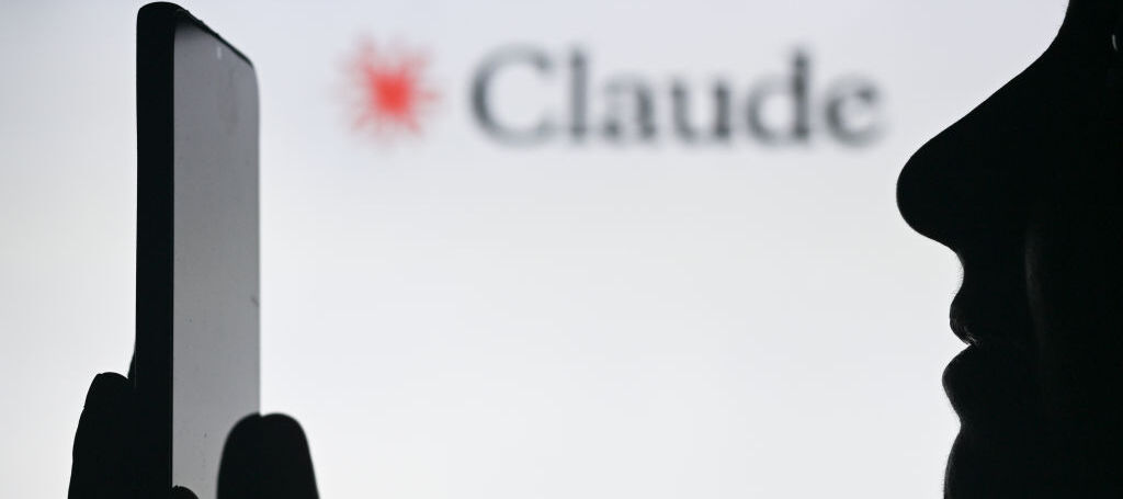 A photo of a person holding a phone in front of a Claude AI display