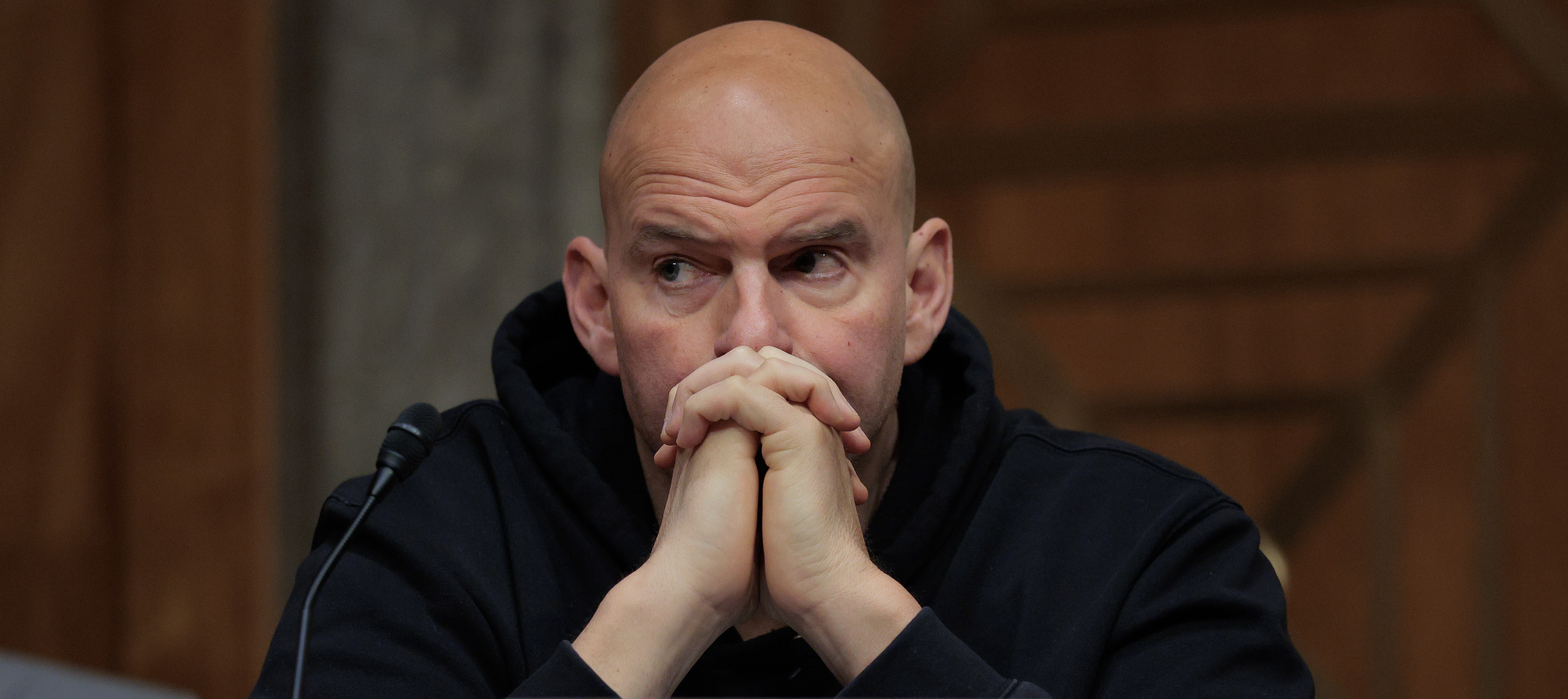 Sen. John Fetterman (D-WV) during a markup hearing in the Dirksen Senate Office Building on Capitol Hill, with his hands folded and leaning against his face.