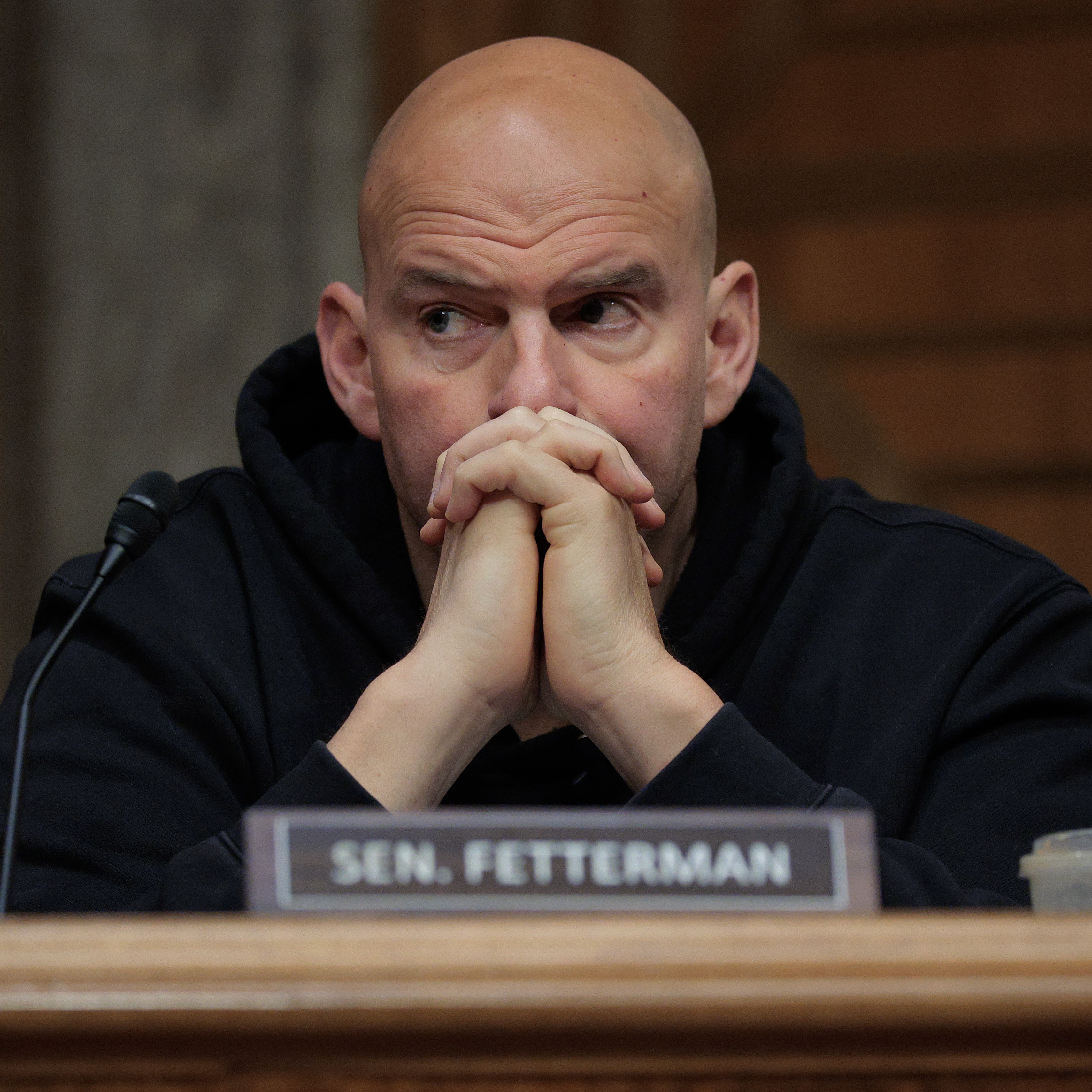 Sen. John Fetterman (D-WV) during a markup hearing in the Dirksen Senate Office Building on Capitol Hill, with his hands folded and leaning against his face.