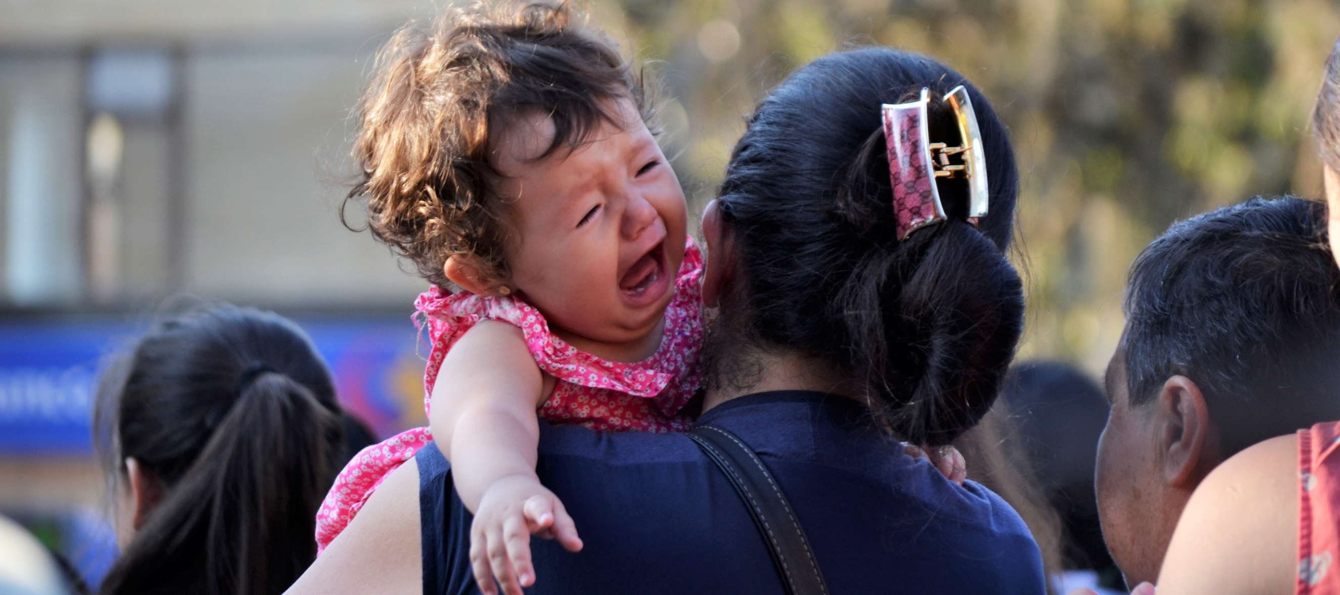 A crying baby on the shoulder of her mother