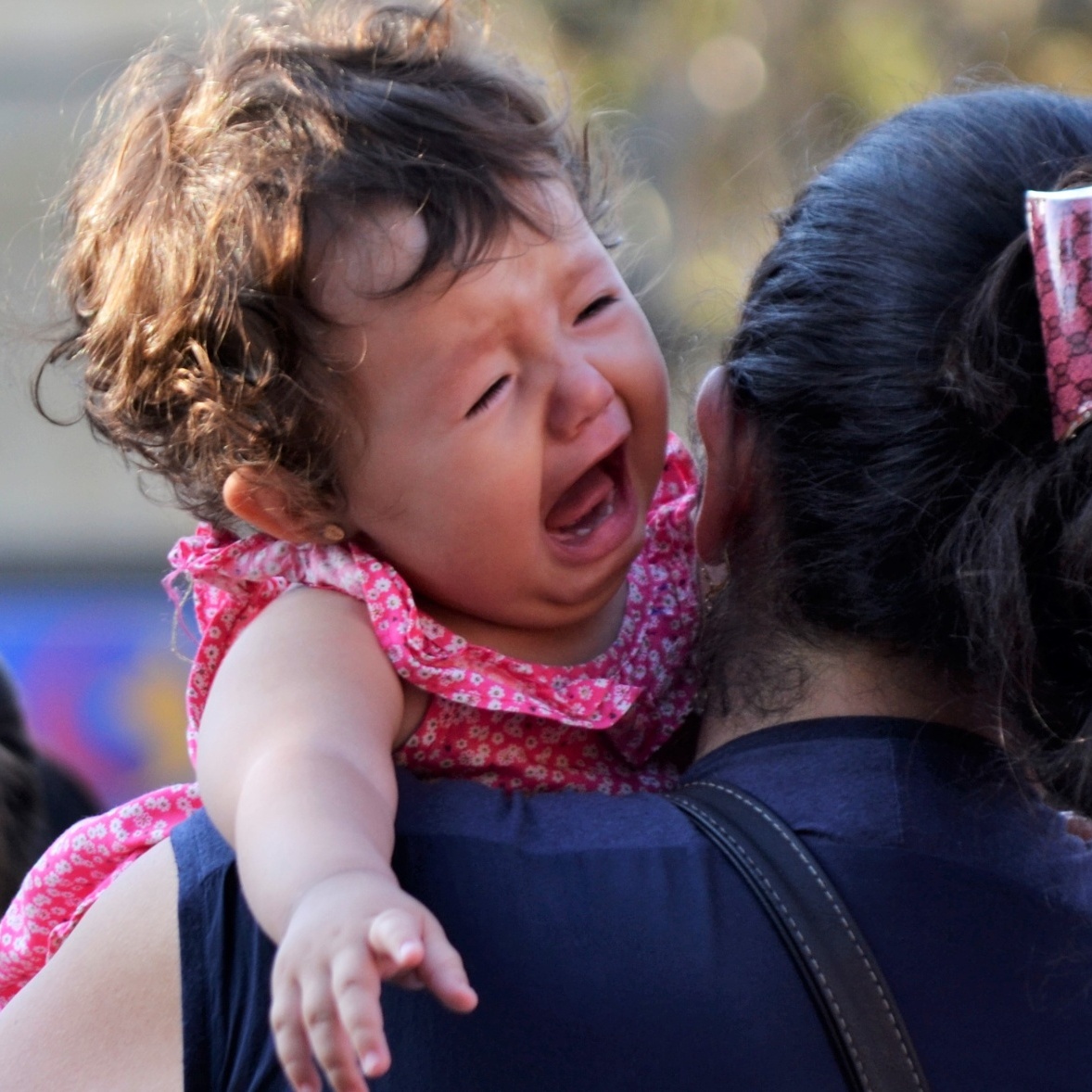 A crying baby on the shoulder of her mother