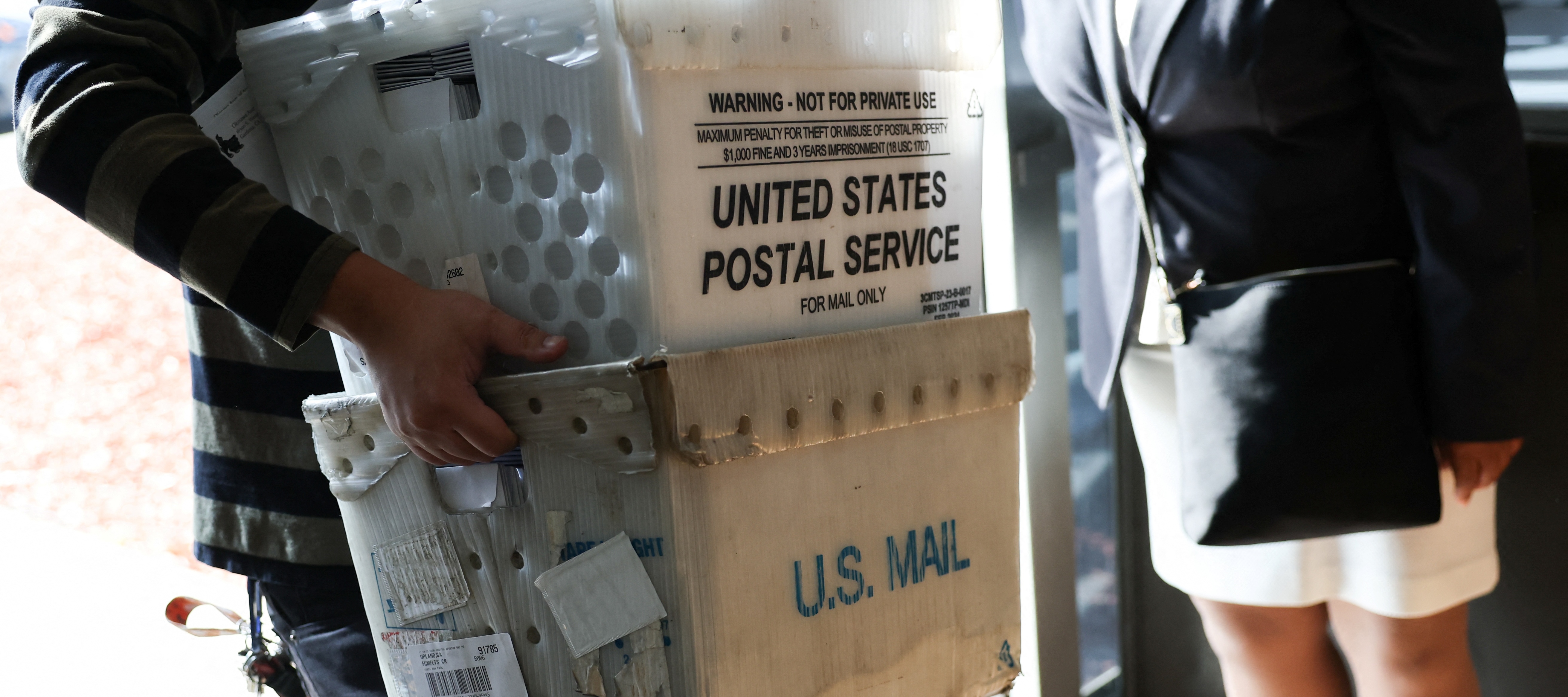 A customer carries packages to be shipped at the USPS Gardena Post Office