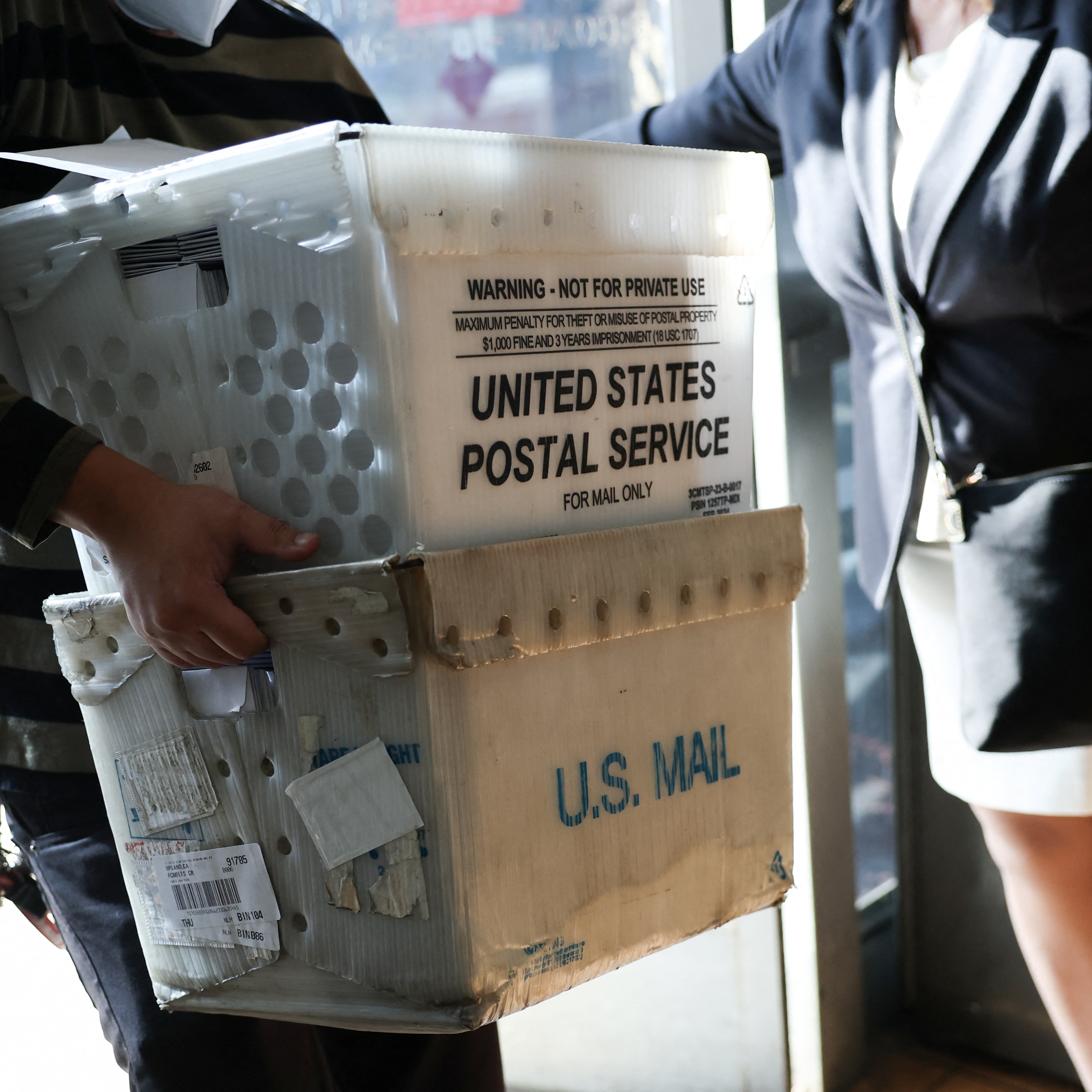 A customer carries packages to be shipped at the USPS Gardena Post Office