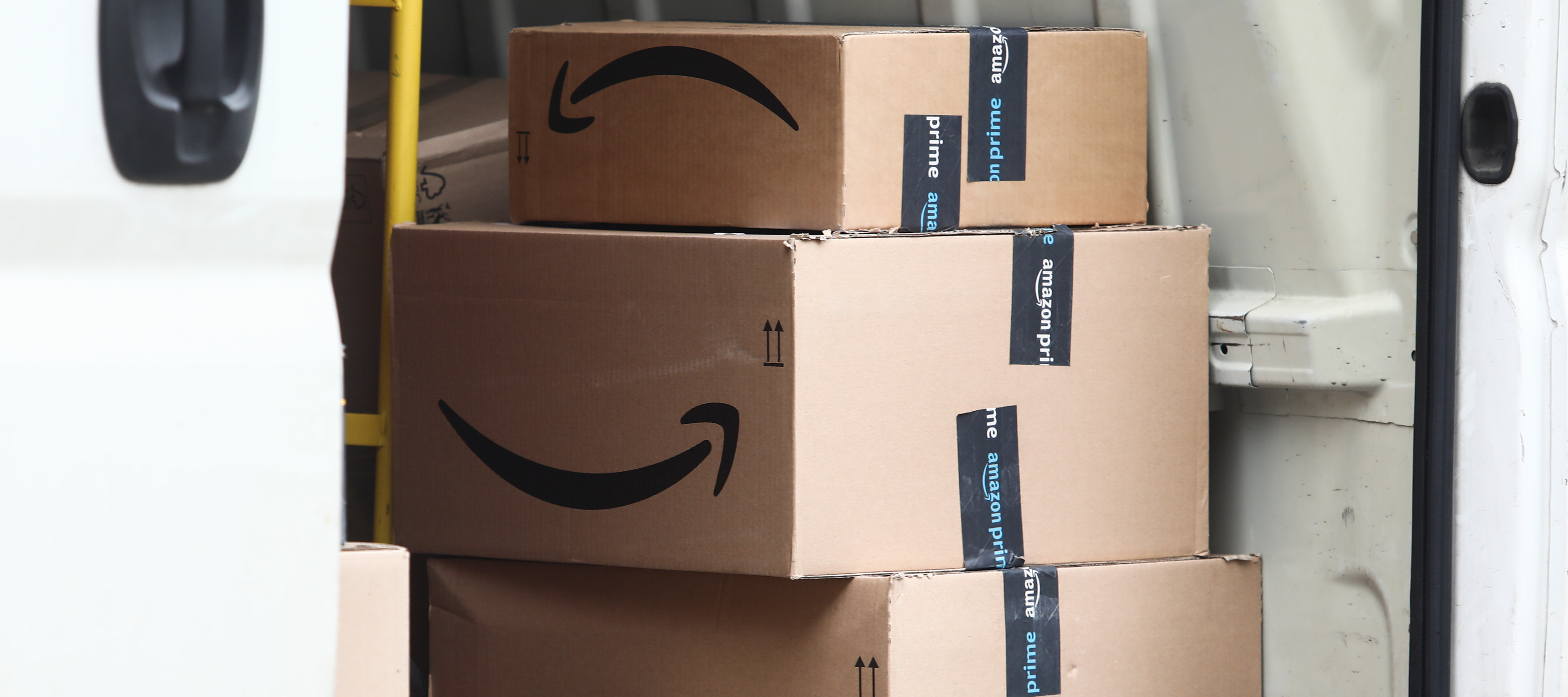 A pile of Amazon delivery boxes sits in a delivery truck.