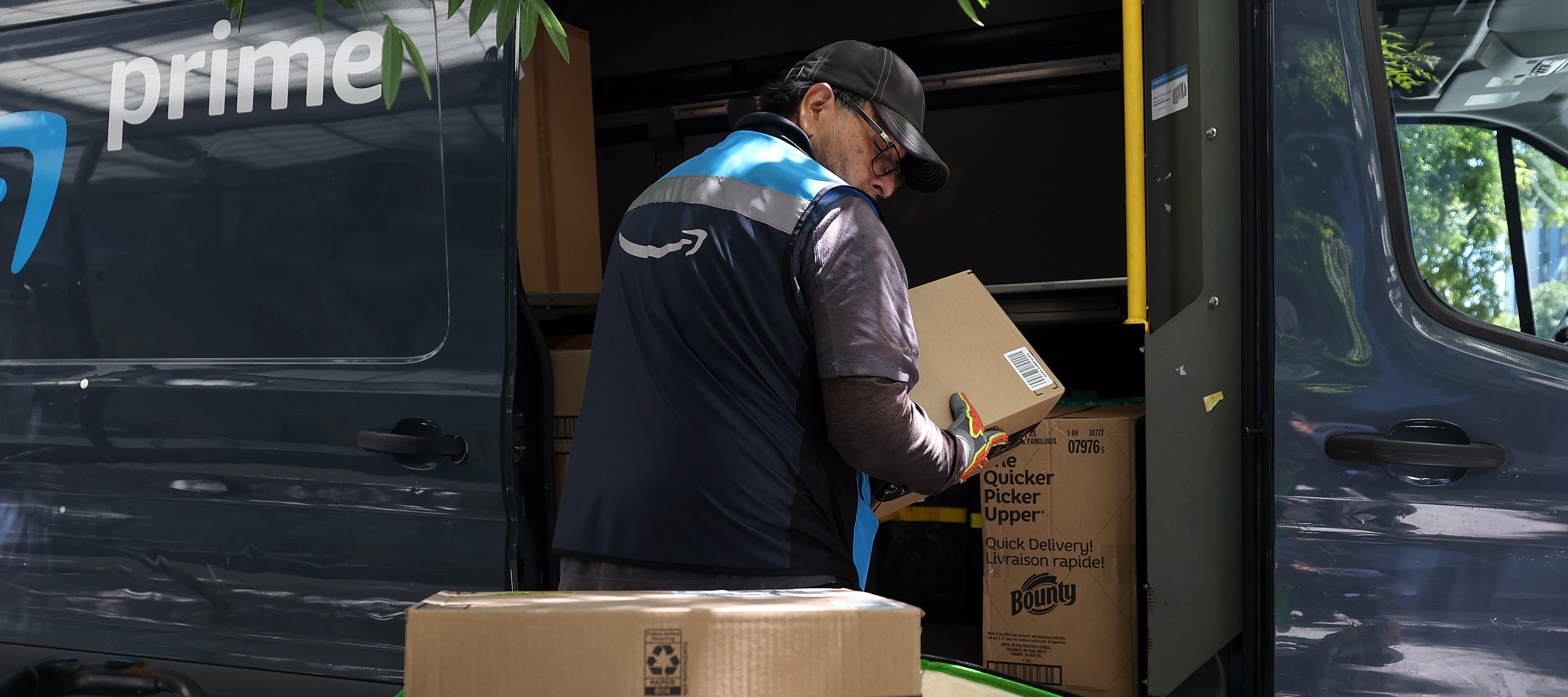 An Amazon delivery person unloads packages from their vehicle.