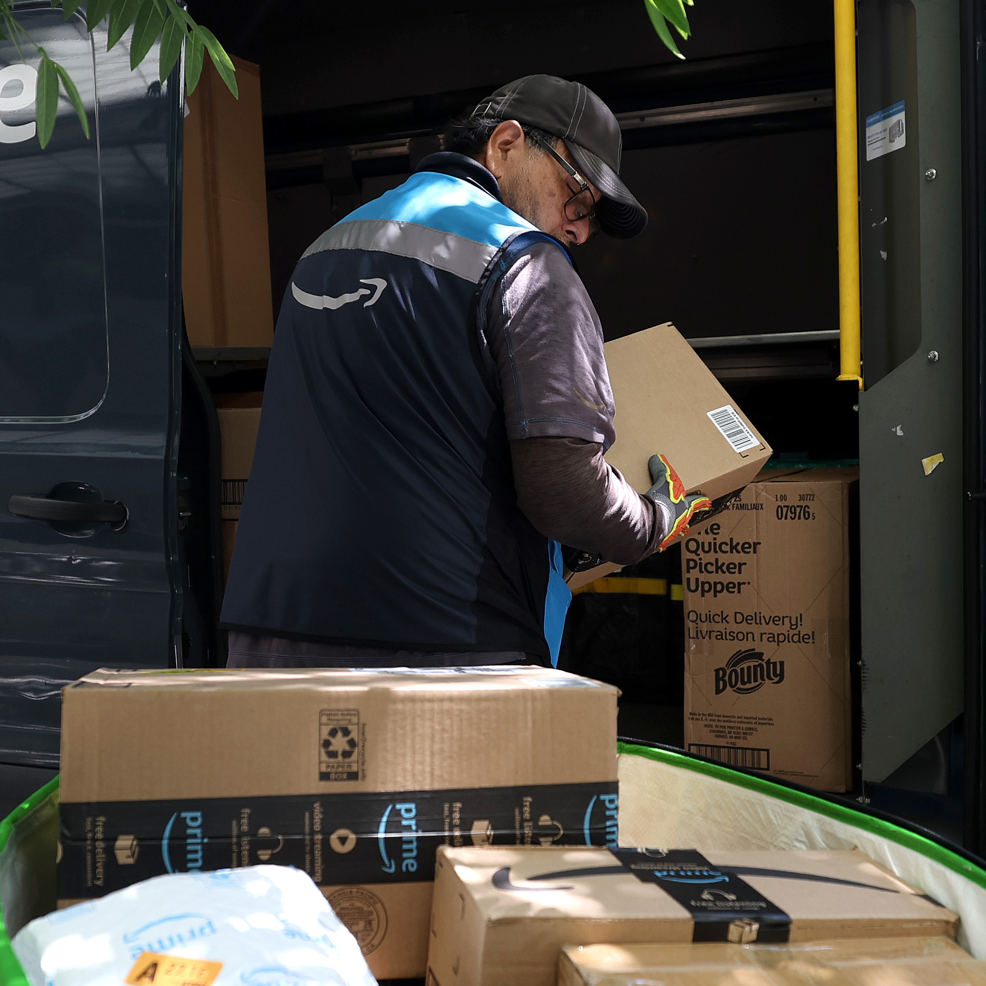An Amazon delivery person unloads packages from their vehicle.