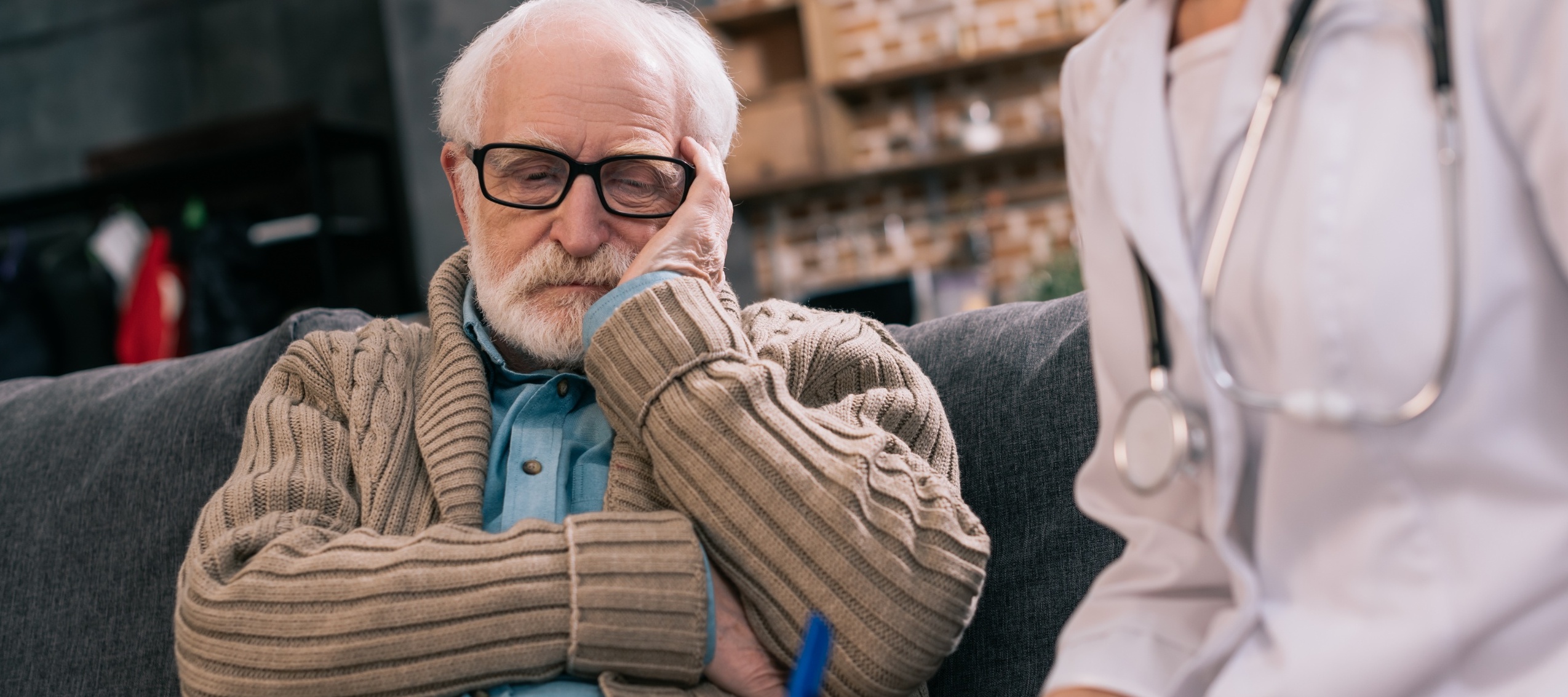 A senior man is worried as he sits with a nurse.