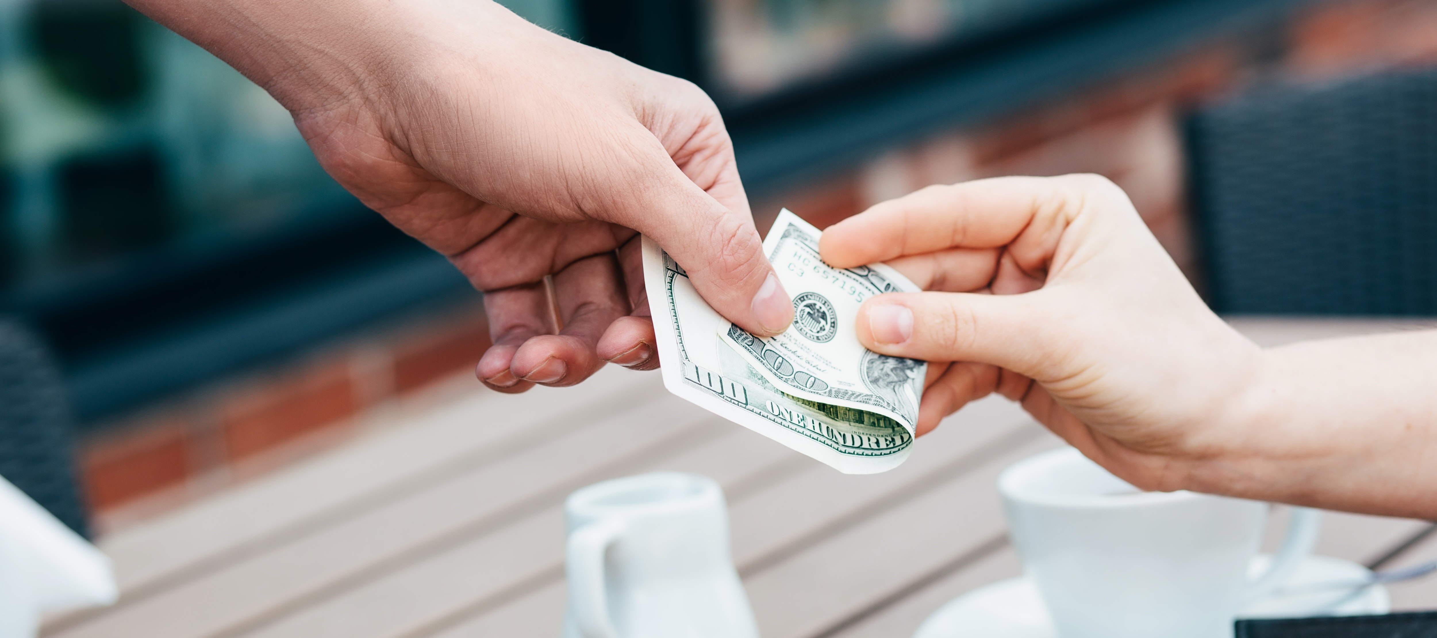 Close-up of someone giving a cash tip to their server at a cafe
