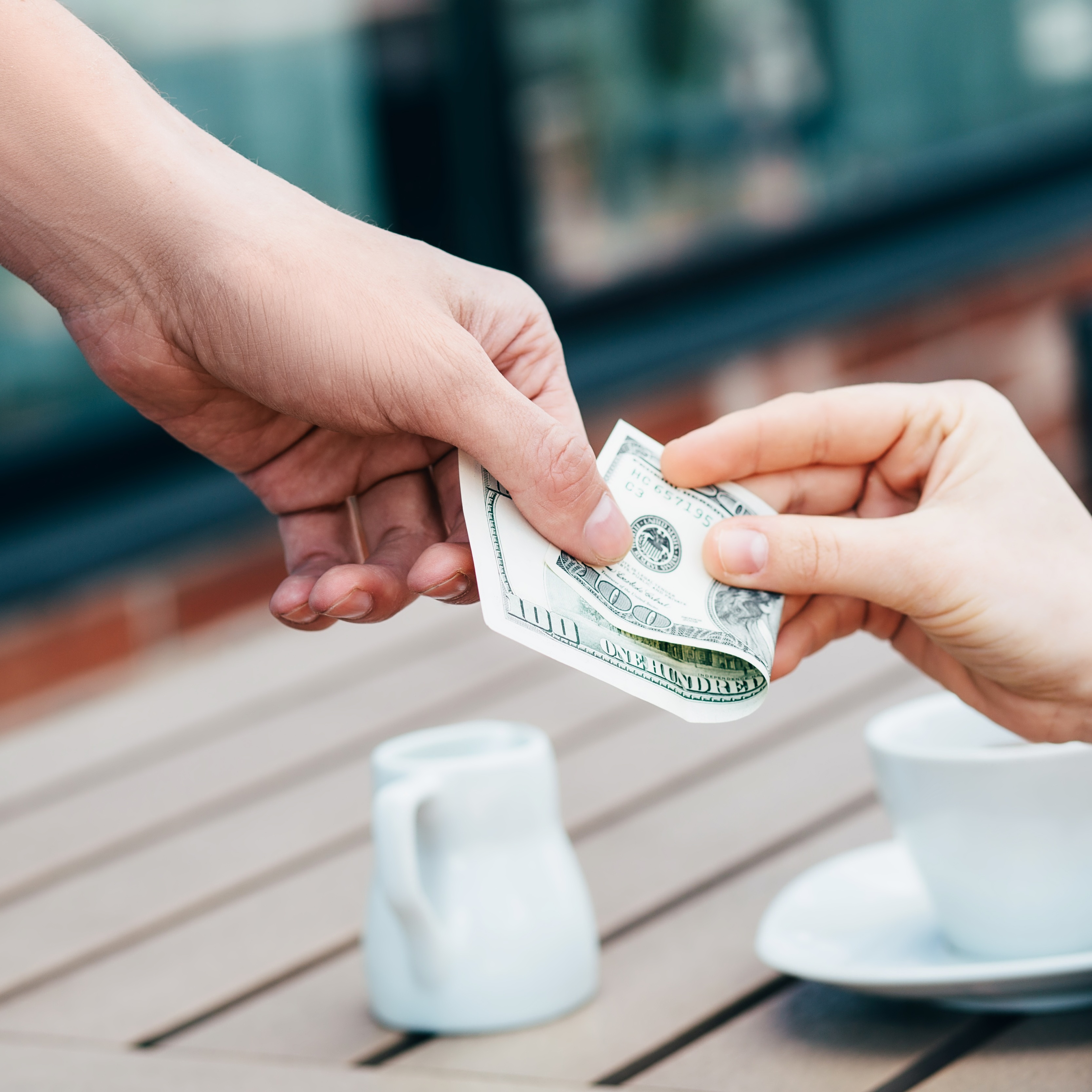 Close-up of someone giving a cash tip to their server at a cafe