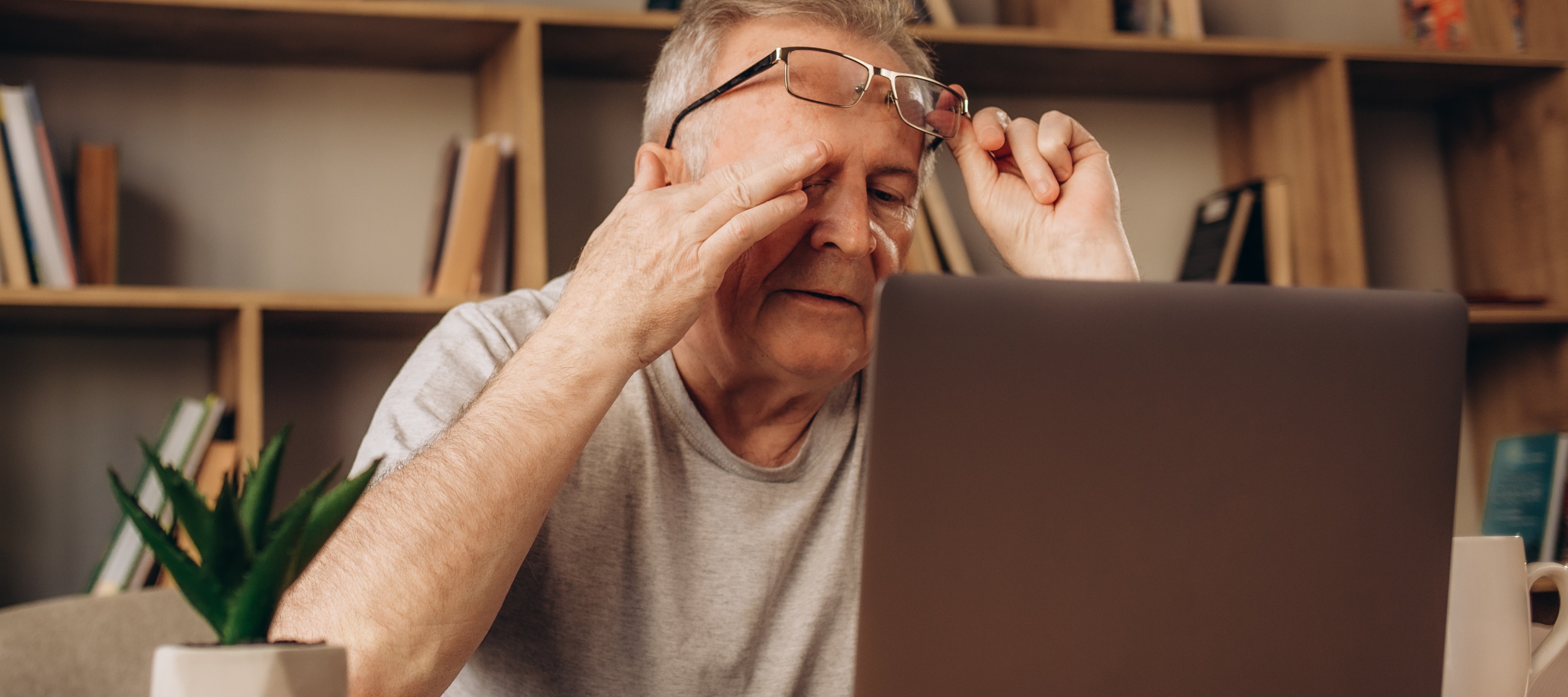 Older man sitting in his office, looking stressed at his computer