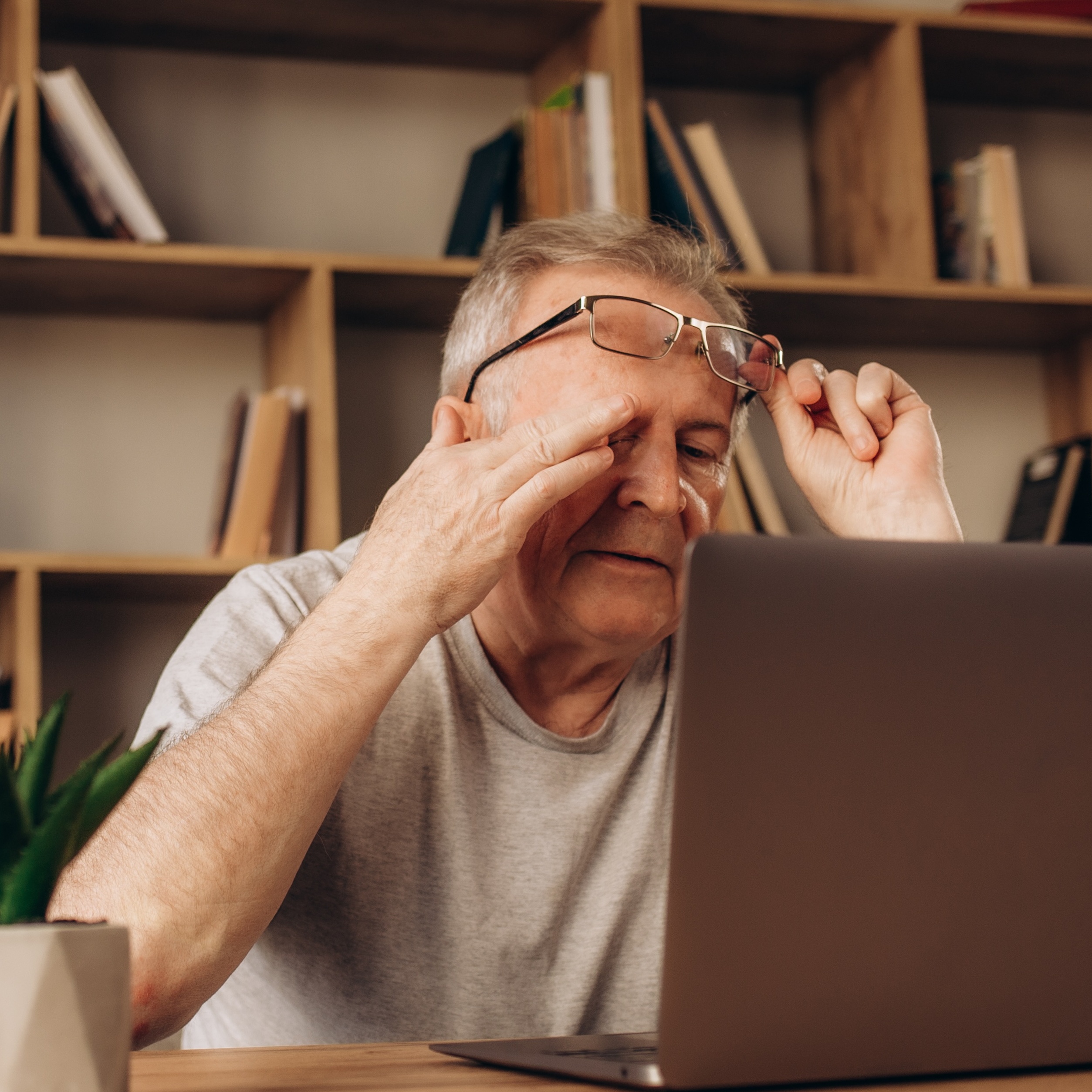 Older man sitting in his office, looking stressed at his computer