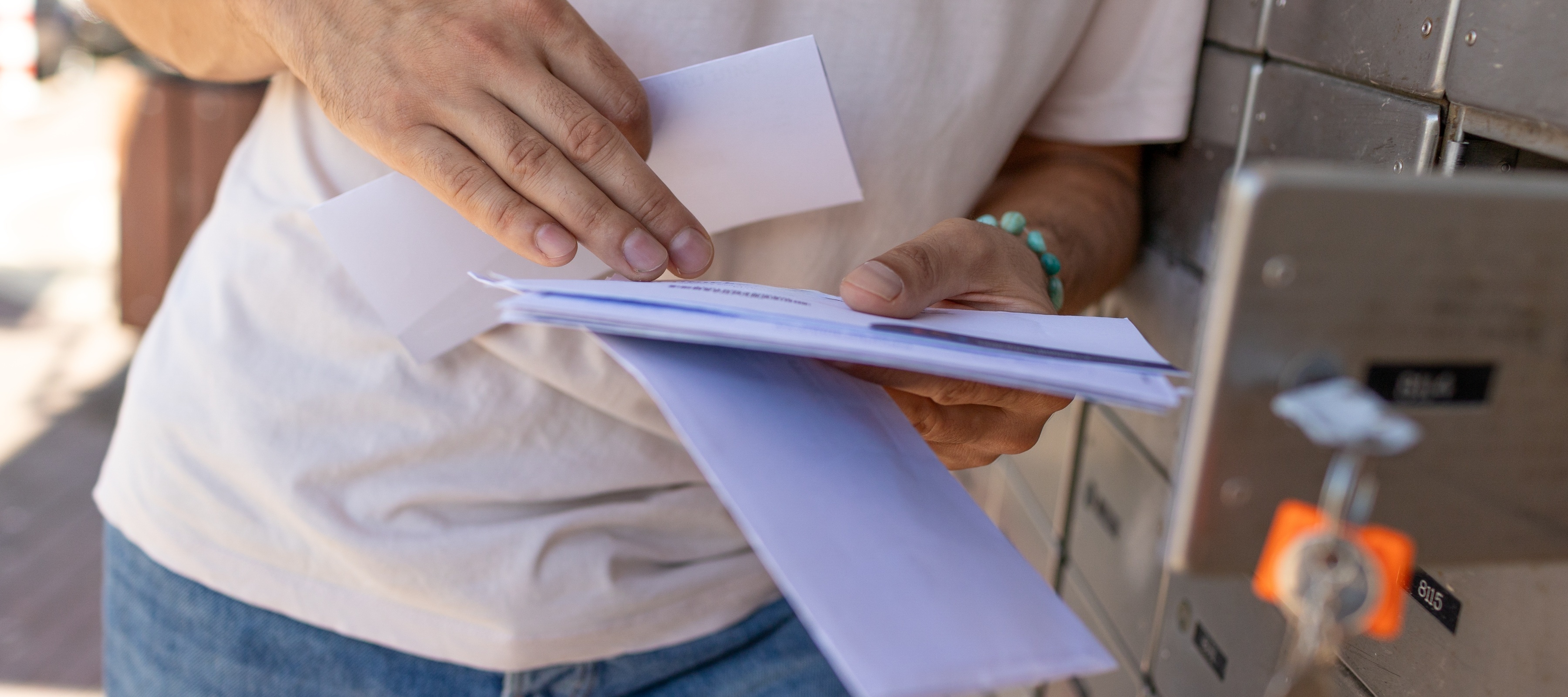 A man look through his mail at the mailbox.