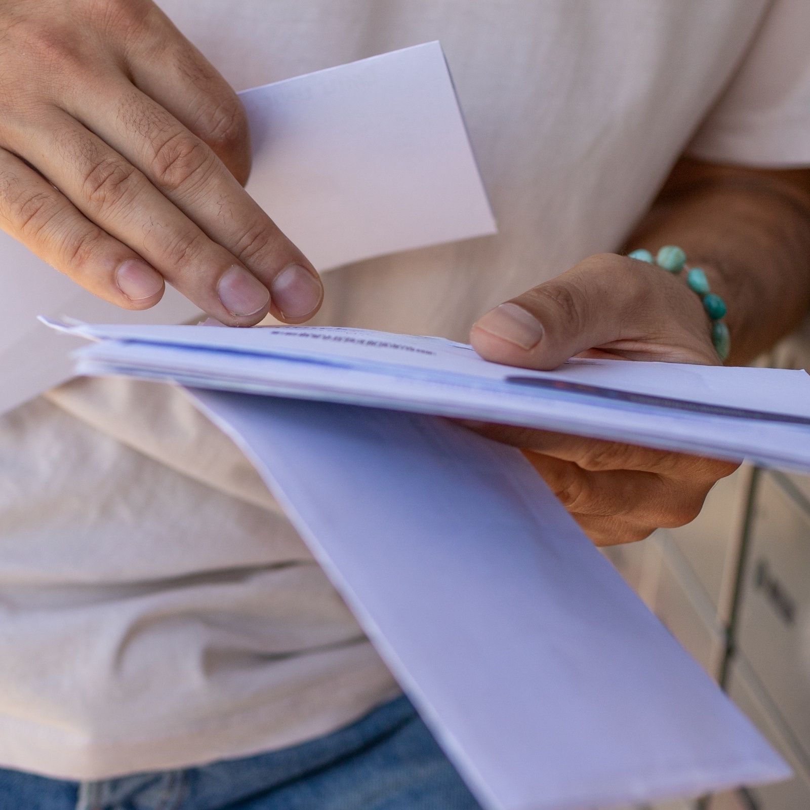 A man look through his mail at the mailbox.