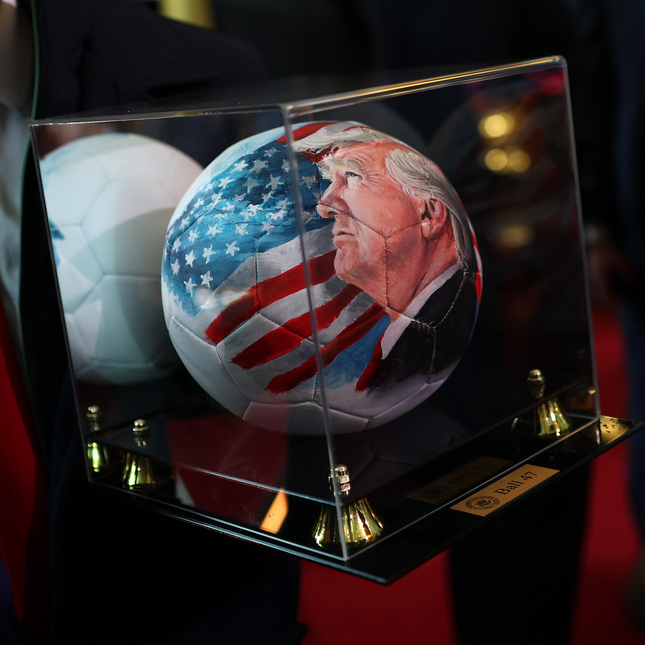 A close up of a soccer ball imprinted with an image of President's Trump's face upon it.