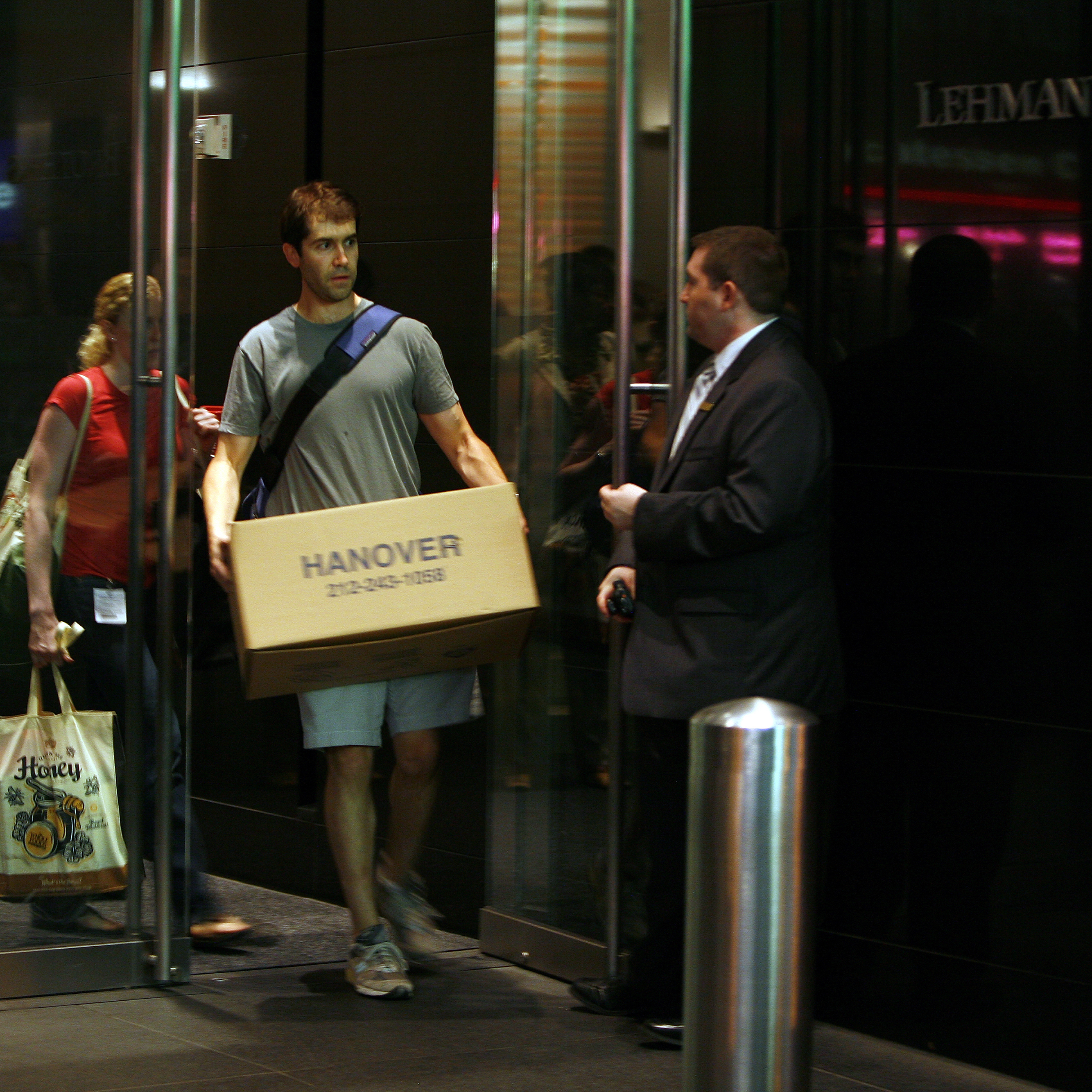 An employee leaves the investment banking house Lehman Brothers, while carrying his private belonging in a box.