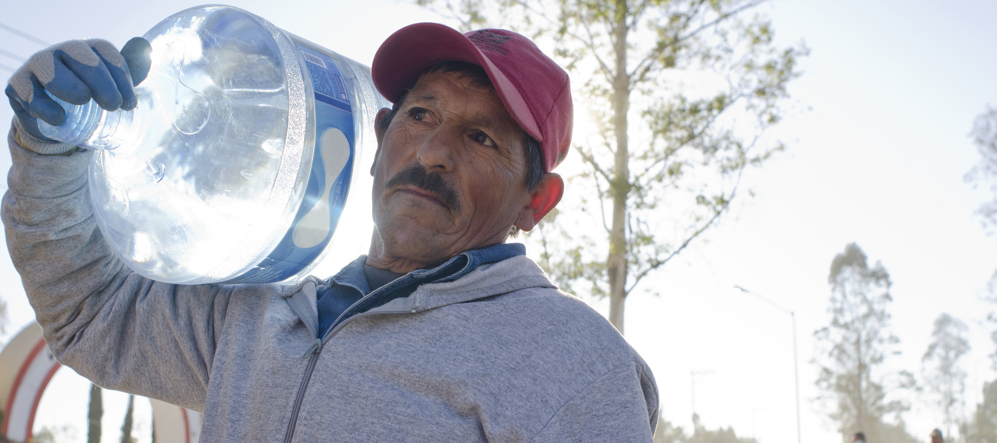 A photo of a man carrying a large jug of water on his shoulder