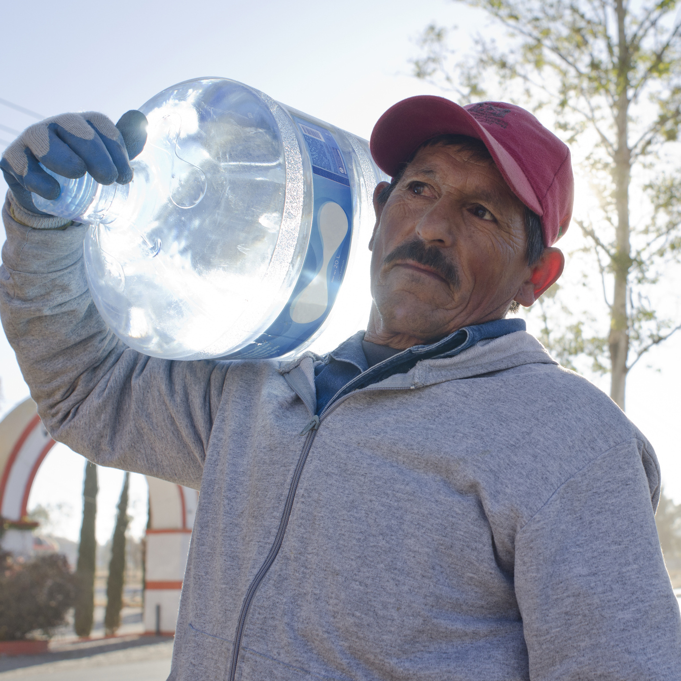 A photo of a man carrying a large jug of water on his shoulder