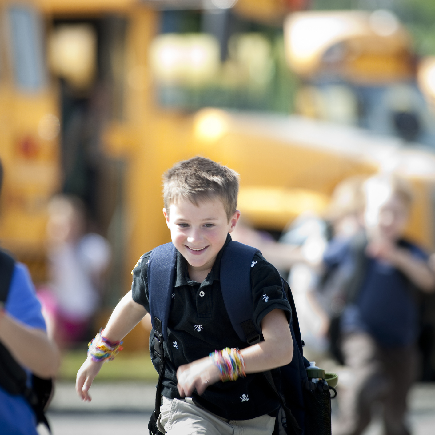 A photo of two male students cheerily running off a school bus