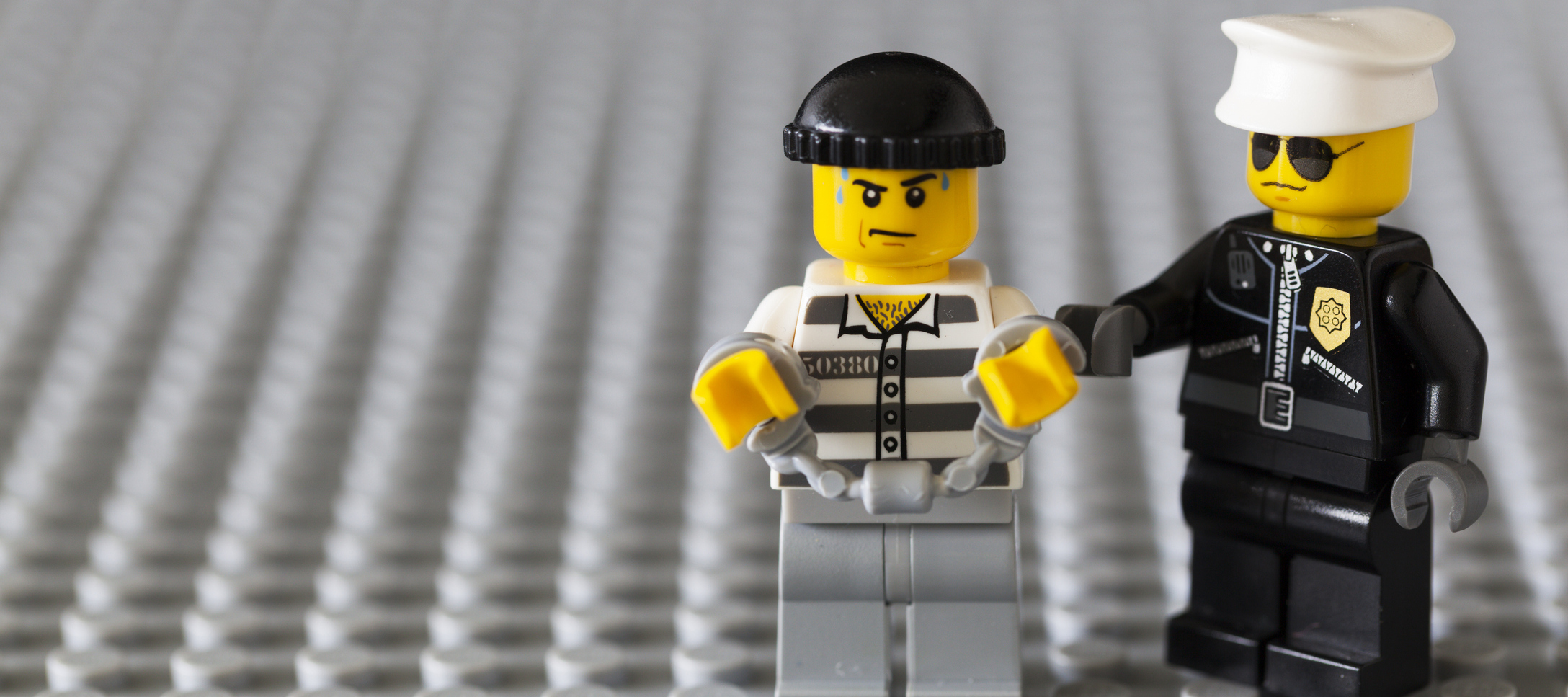 A photo of a Lego police man handcuffing a lego bandit