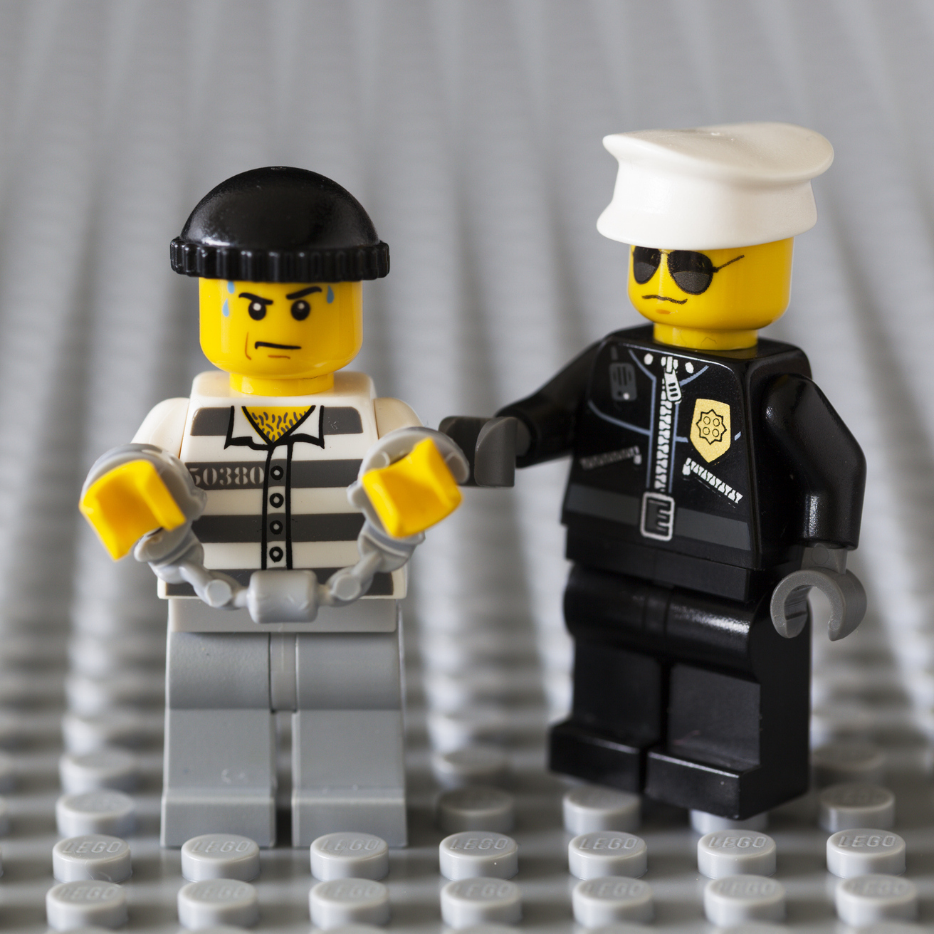 A photo of a Lego police man handcuffing a lego bandit