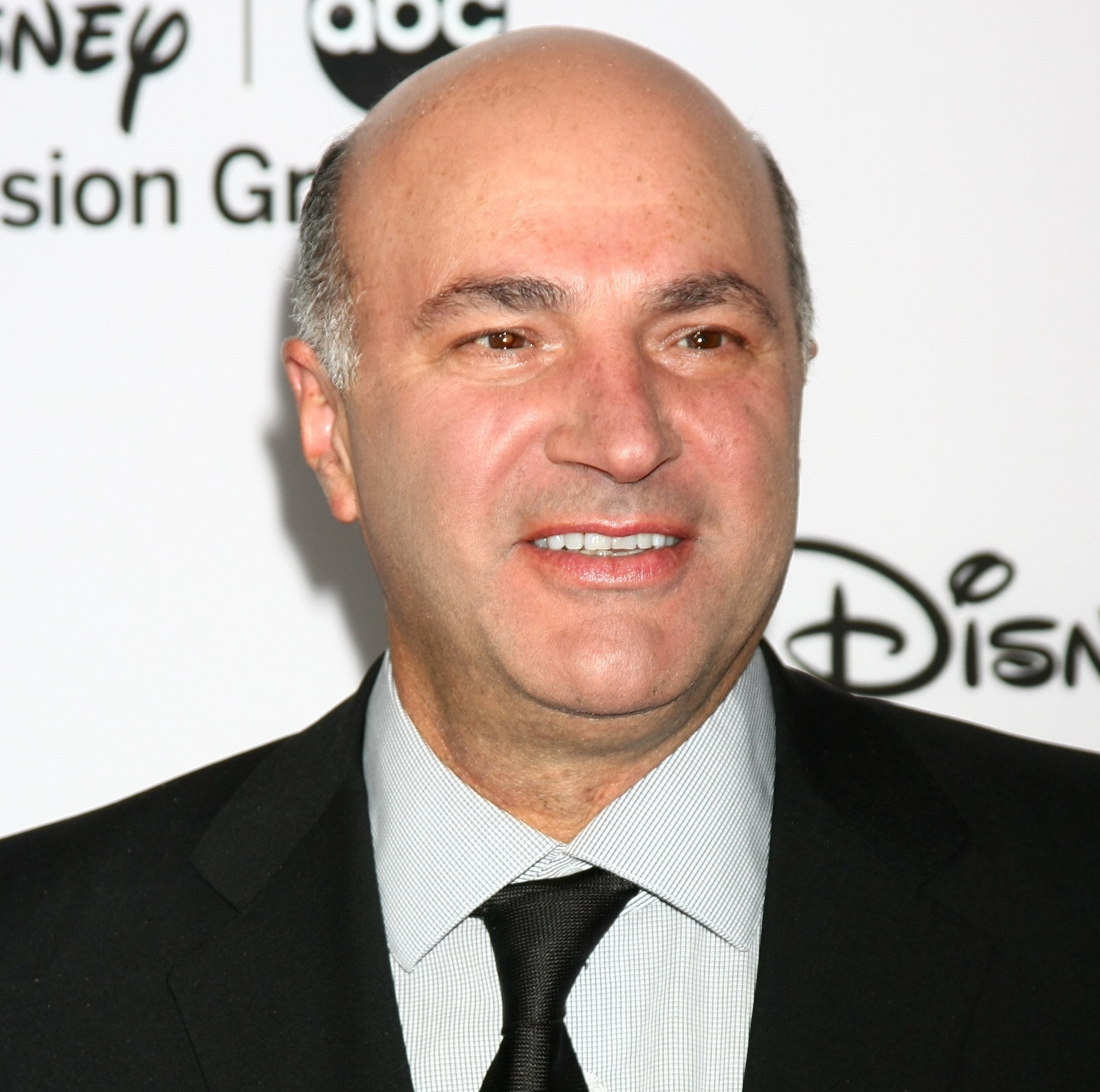 Split screen image of Kevin O'Leary talking, Zohran Mamdani turning over his shoulder scowling.