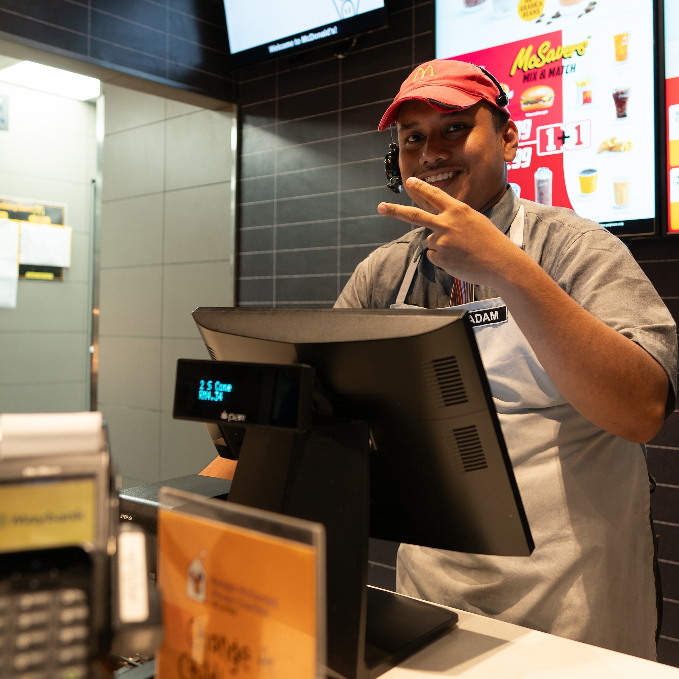 A McDonald's worker gives the victory sign with his hands.