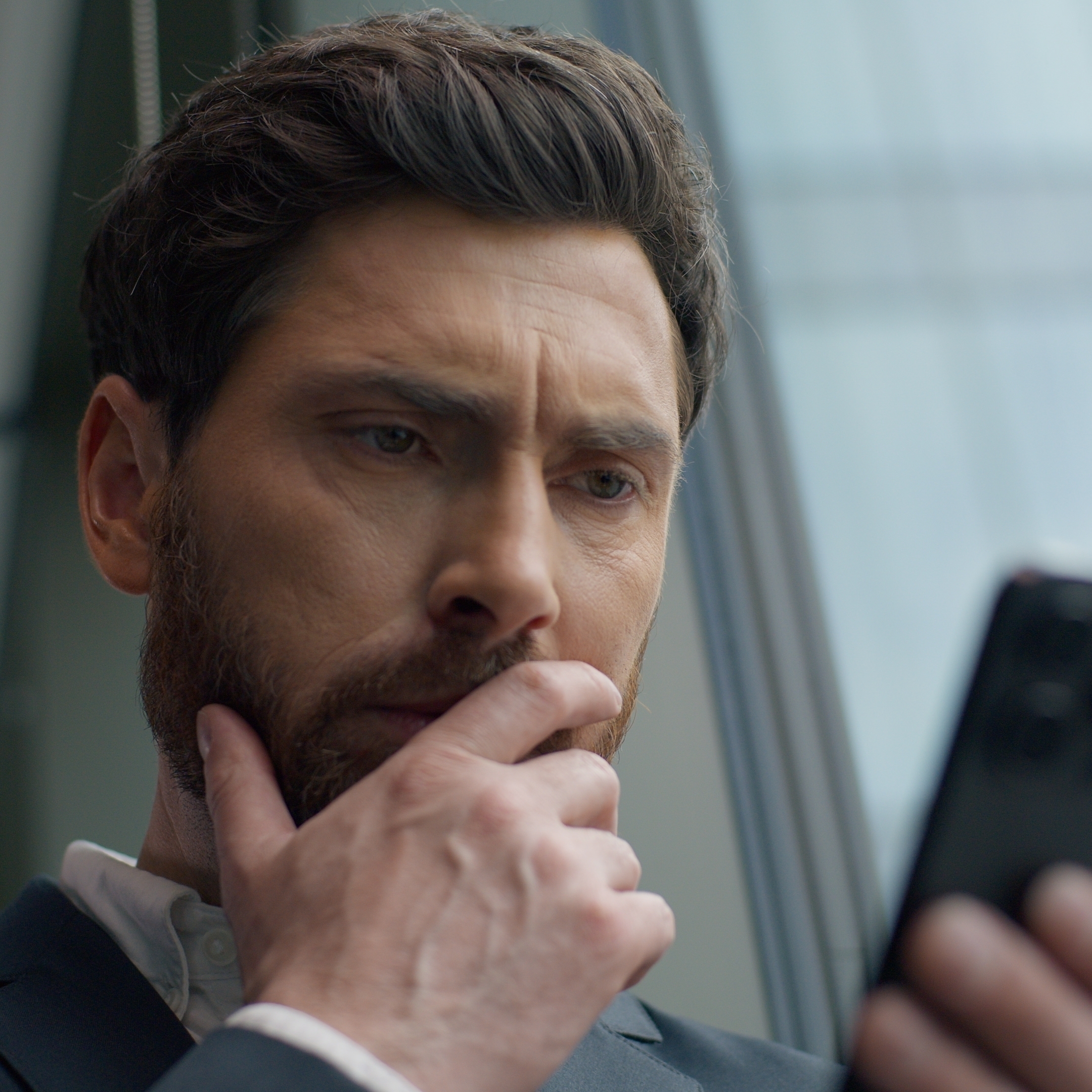 Pensive, middle-aged man looking down at his phone.