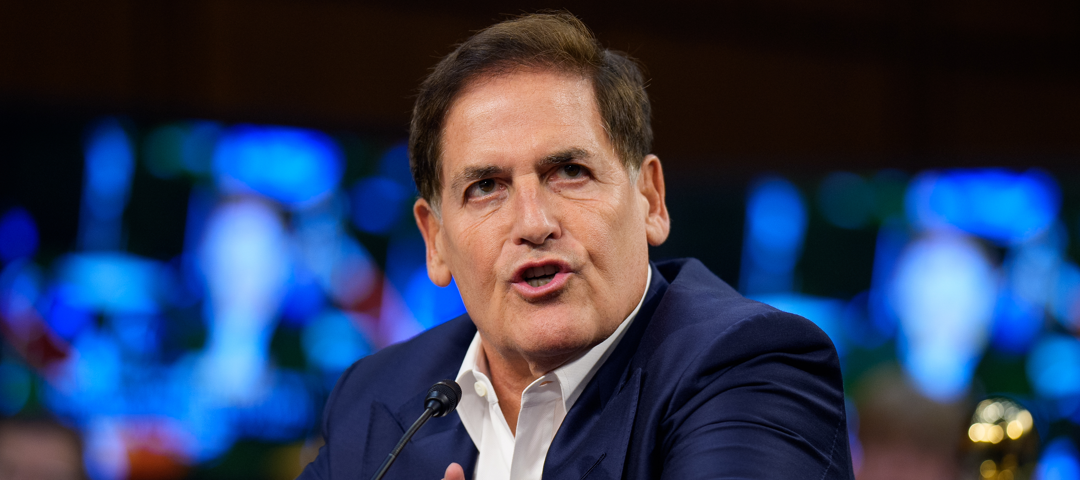 Mark Cuban speaks during a Senate Committee seated before a microphone.