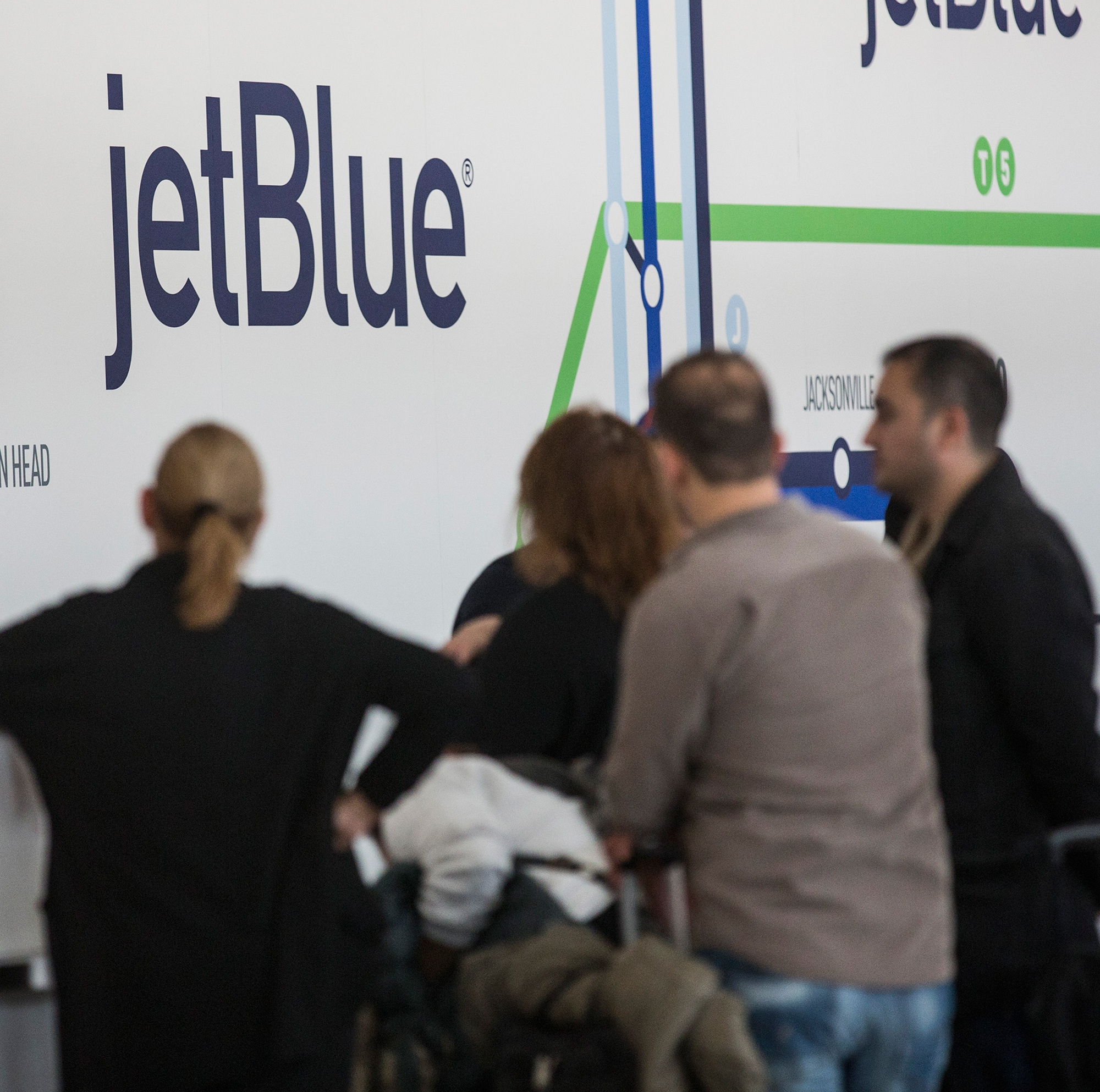 Customers gather around a JetBlue counter at John F. Kennedy Airport.