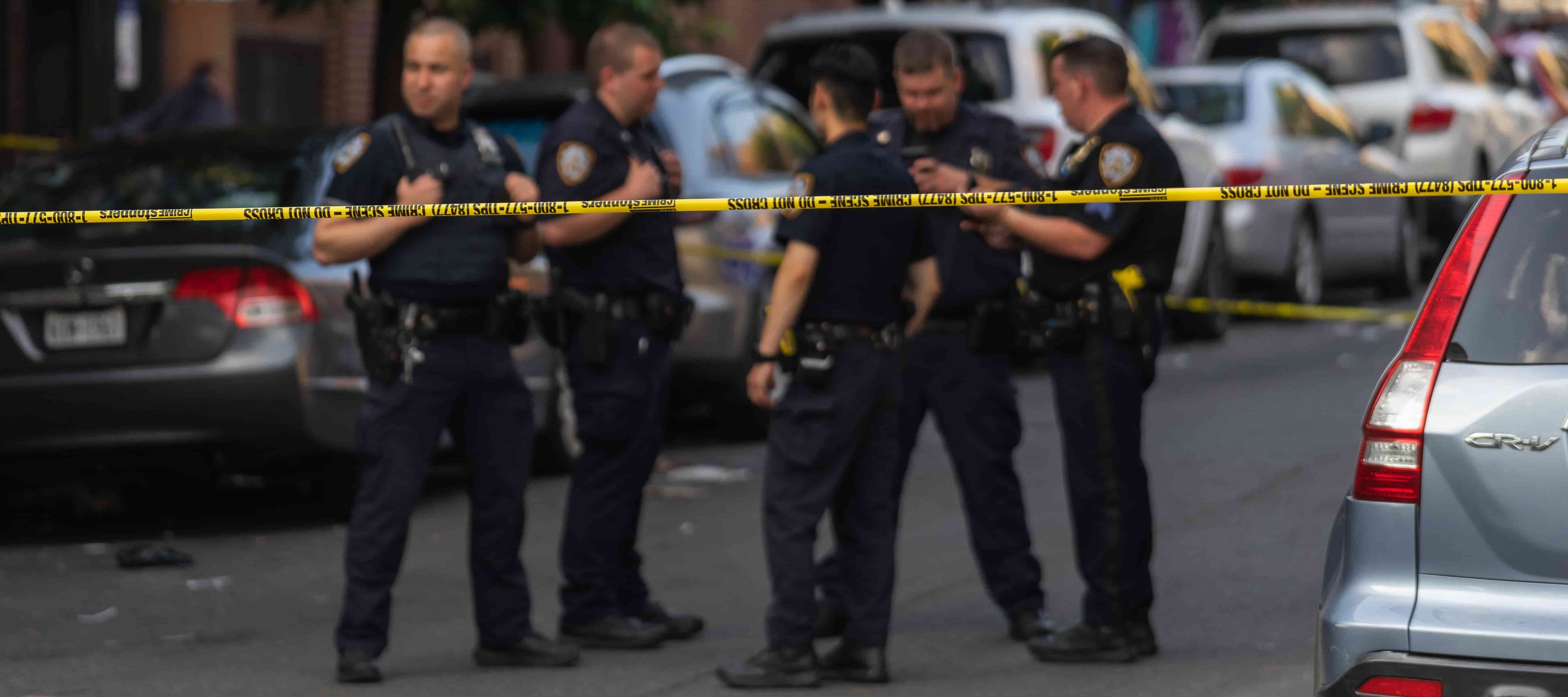 A photo of police officers behind police tape at a crime scene