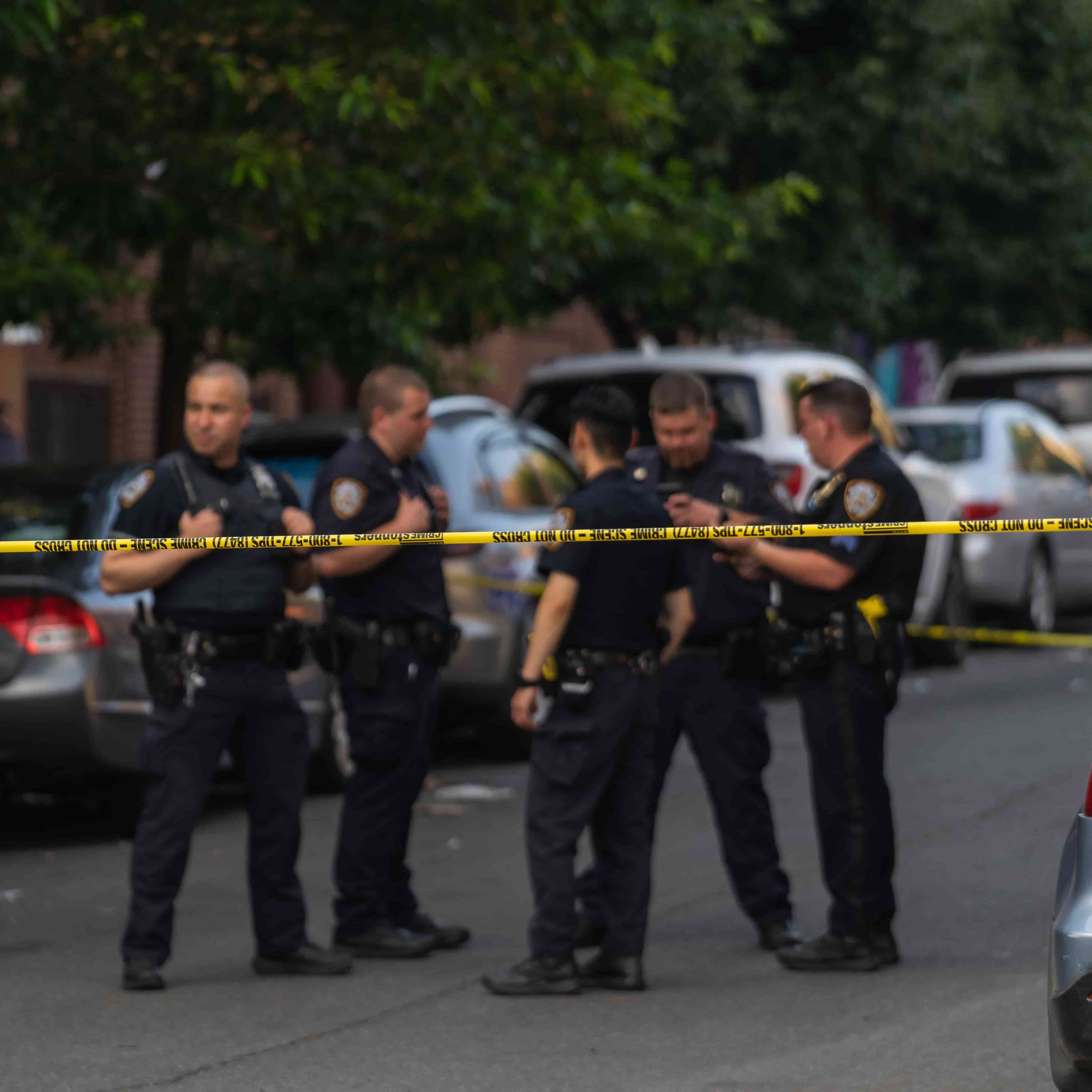 A photo of police officers behind police tape at a crime scene