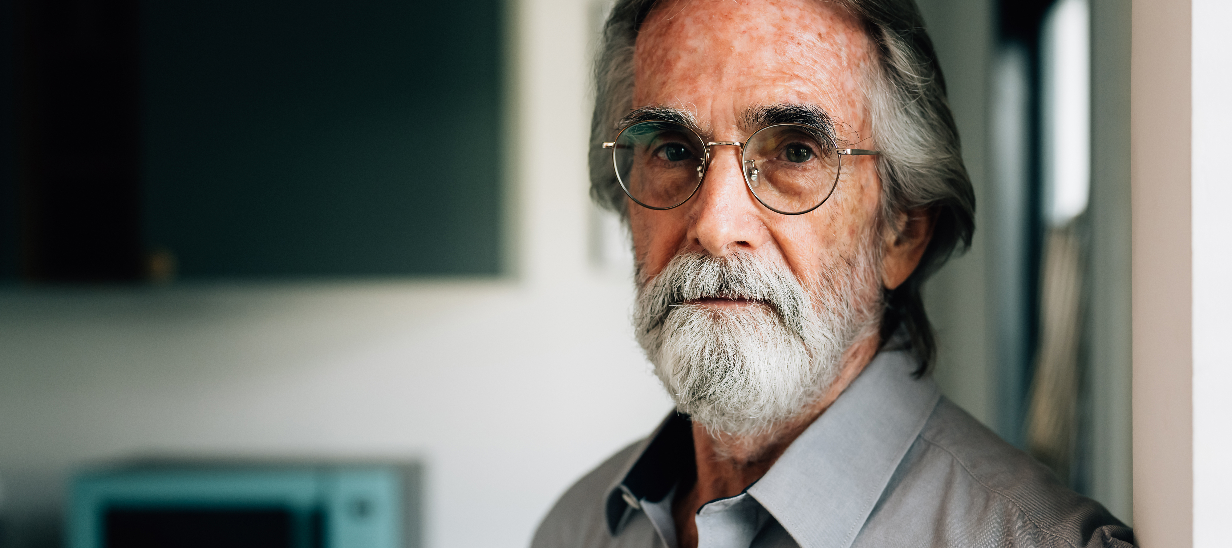 A retired gentleman looks pensively towards the camera.