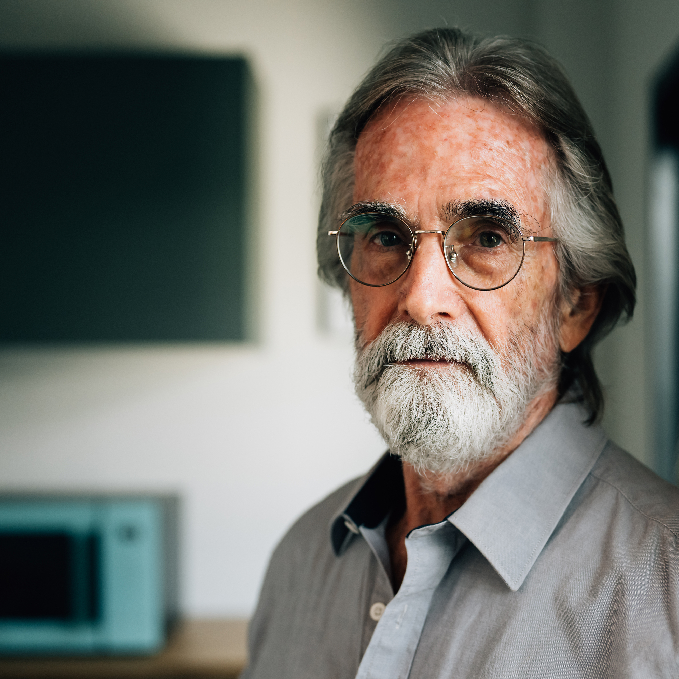 A retired gentleman looks pensively towards the camera.