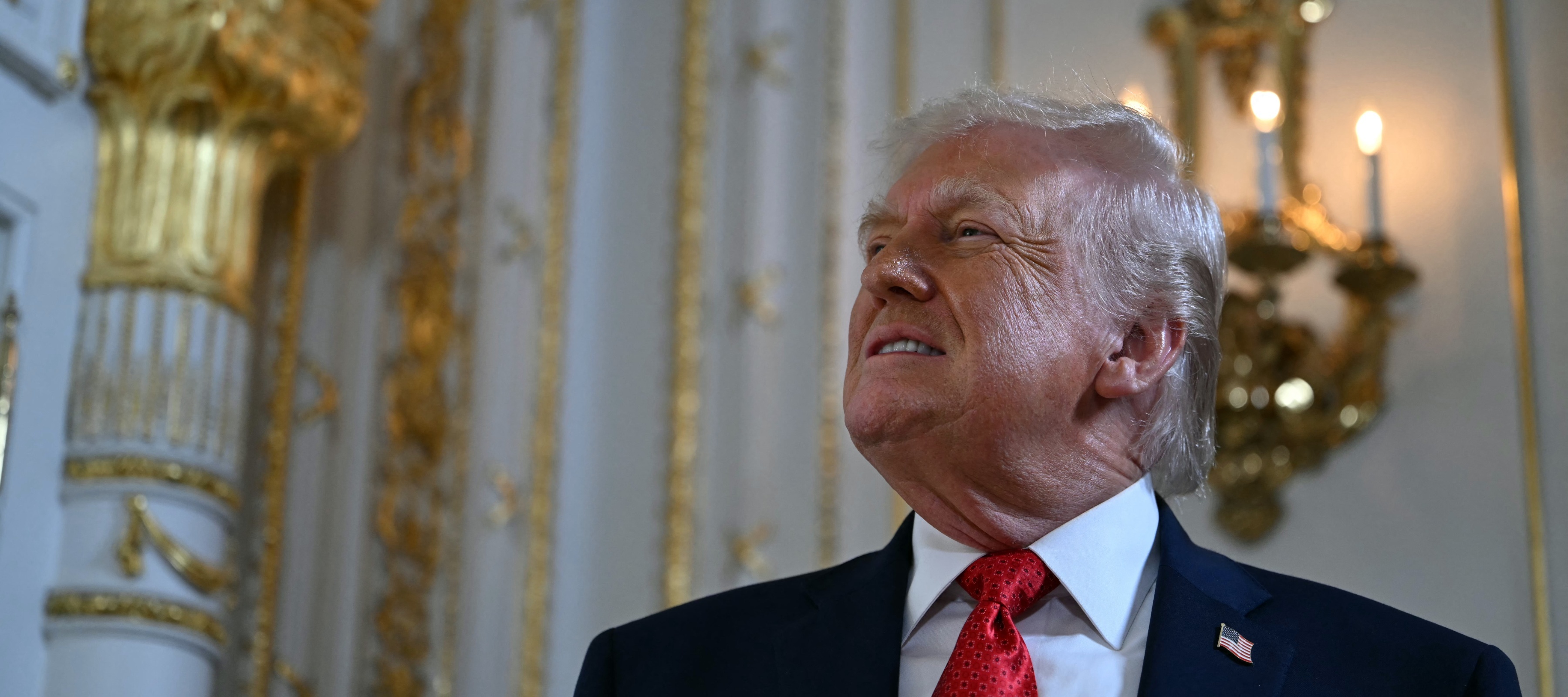 Trump smiles in the White House while looking at his golden ballroom