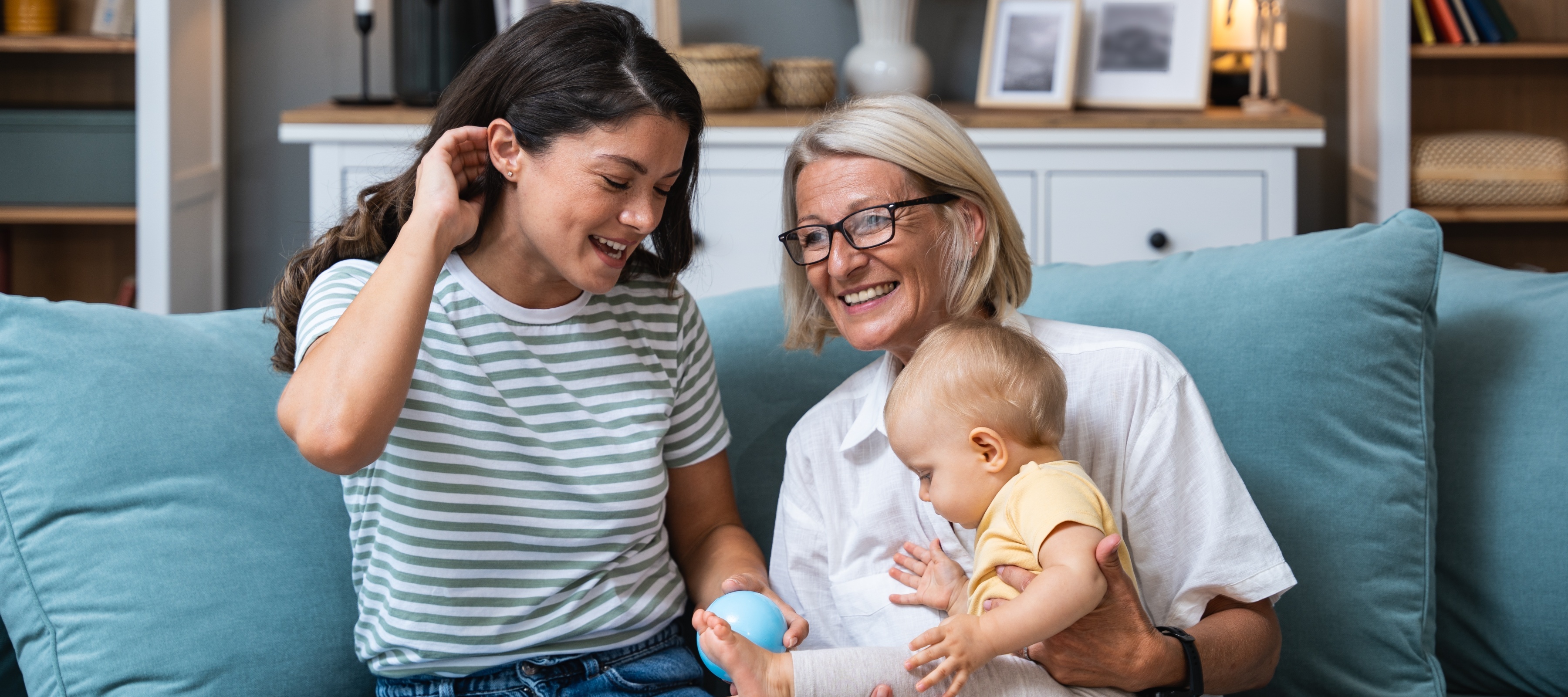 A young woman and her older mother hold her baby daughter together