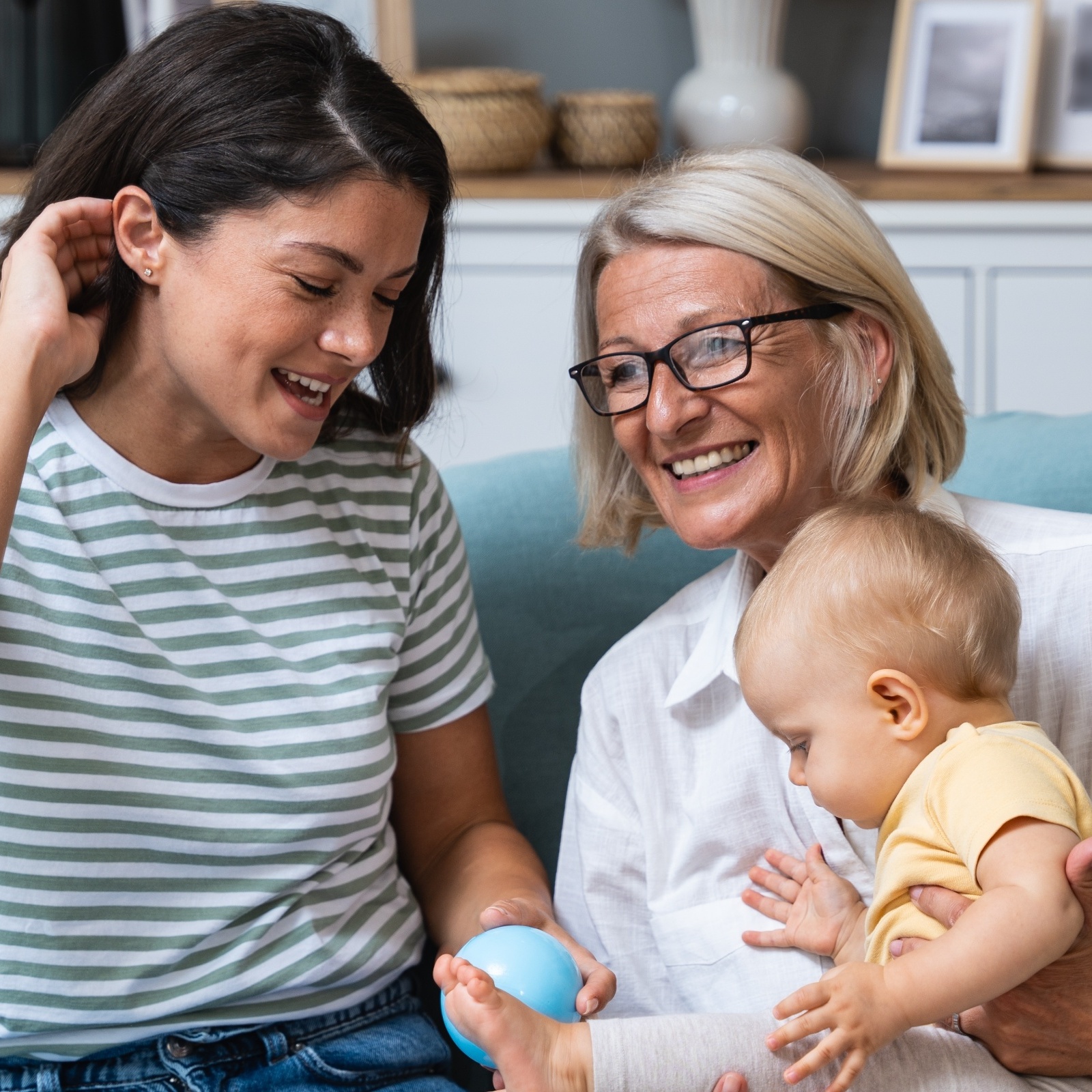 A young woman and her older mother hold her baby daughter together