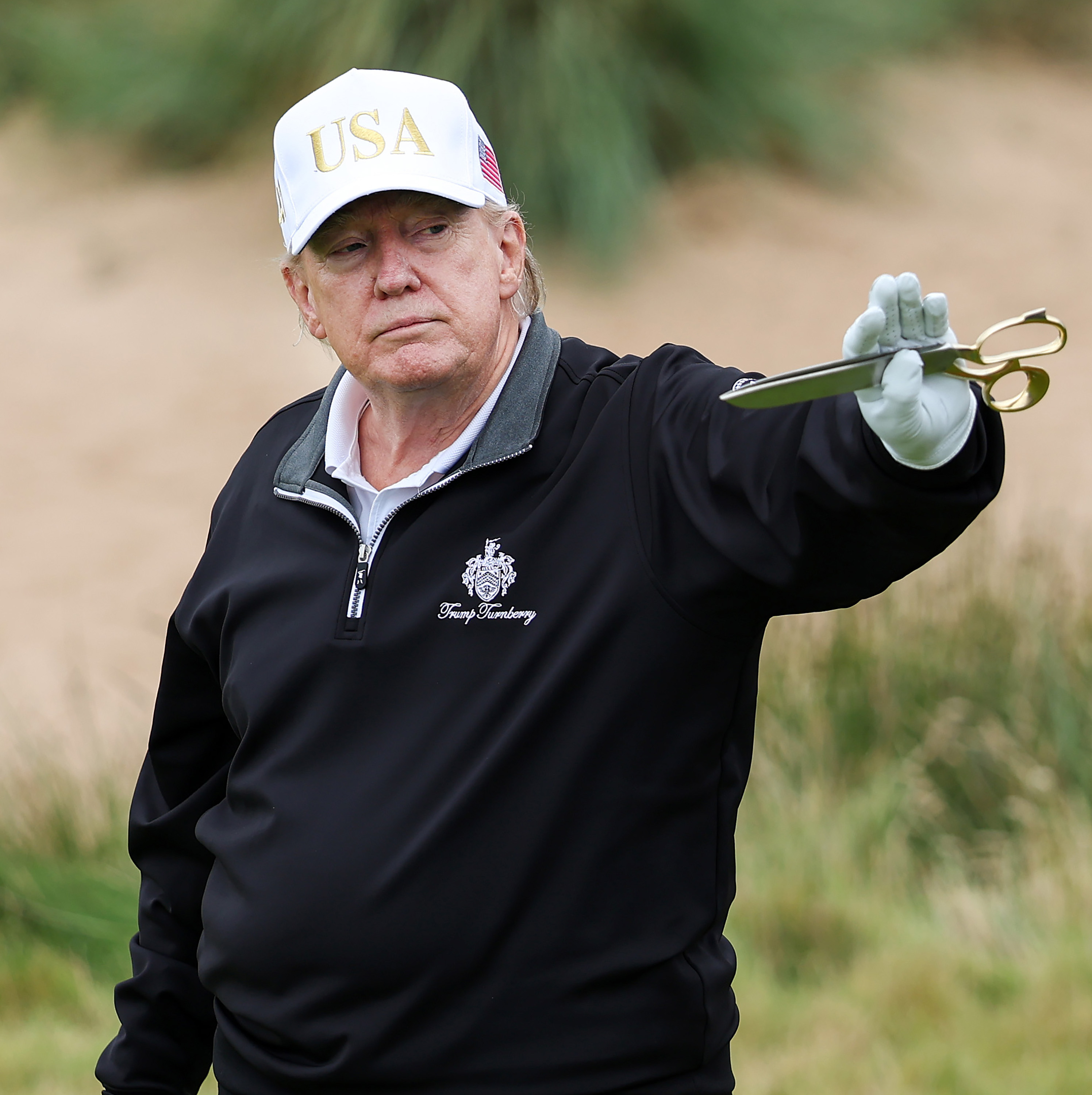 Donald Trump holds up a pair of scissor after cutting the ribbon for his his new golf course at his Trump International Golf links resort in Balmedie, Scotland.
